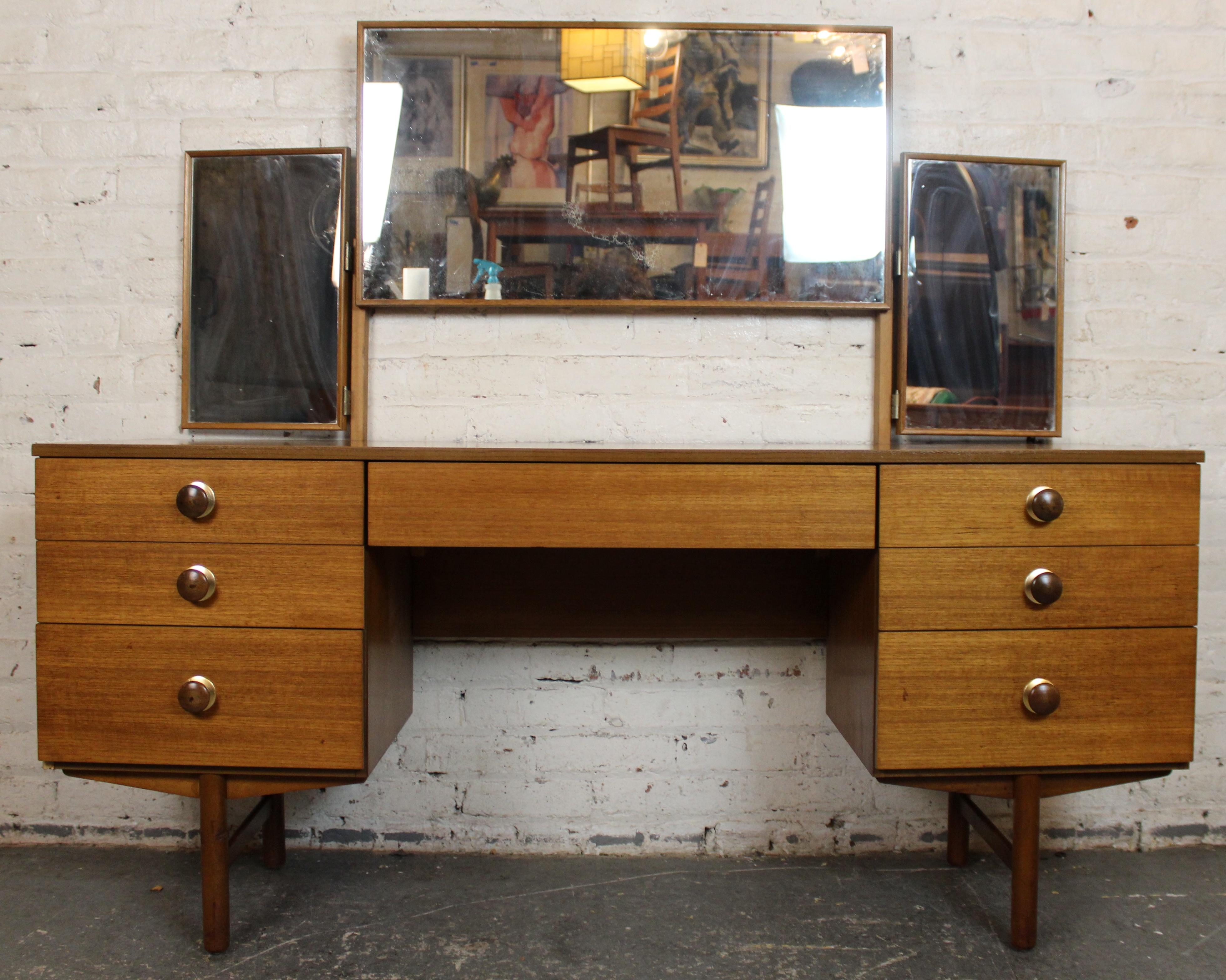 Élégante coiffeuse en teck du milieu du siècle, dotée d'une surface magnifiquement grainée et d'un miroir réglable en trois parties - un grand panneau central qui se replie, flanqué de deux miroirs latéraux plus petits qui pivotent pour obtenir