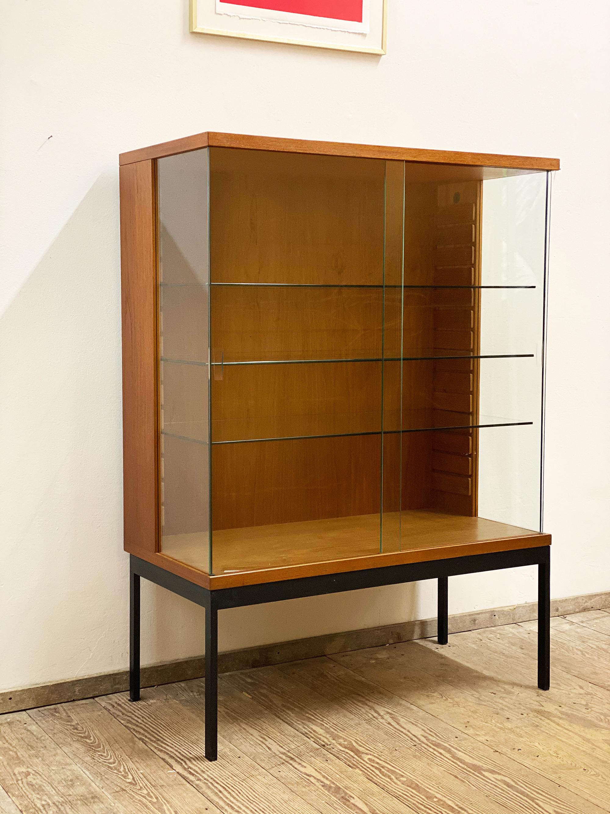 Dimensions 86 x 43 x 119 cm (W x D x H)

Elegant Dieter Wäckerlin glass cabinet in teak veneer with a nice grain. The minimalist sideboard sits on a black metal base and has glass corners in the front. This is a rare showcase from Waeckerlins