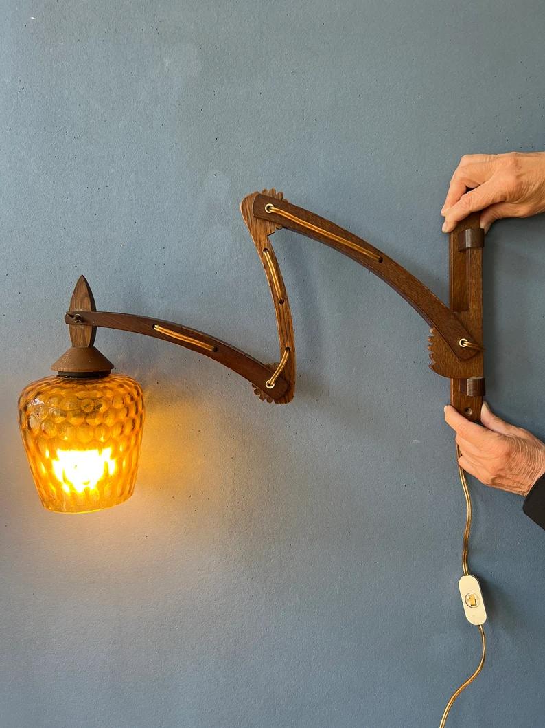One of a kind mid century wall lamp with wooden frame and glass shade. The wooden arm can be extended by adjusting the small arms. It can stretch out all the way. The lamp requires an E27 (standard) lightbulb and currently has an