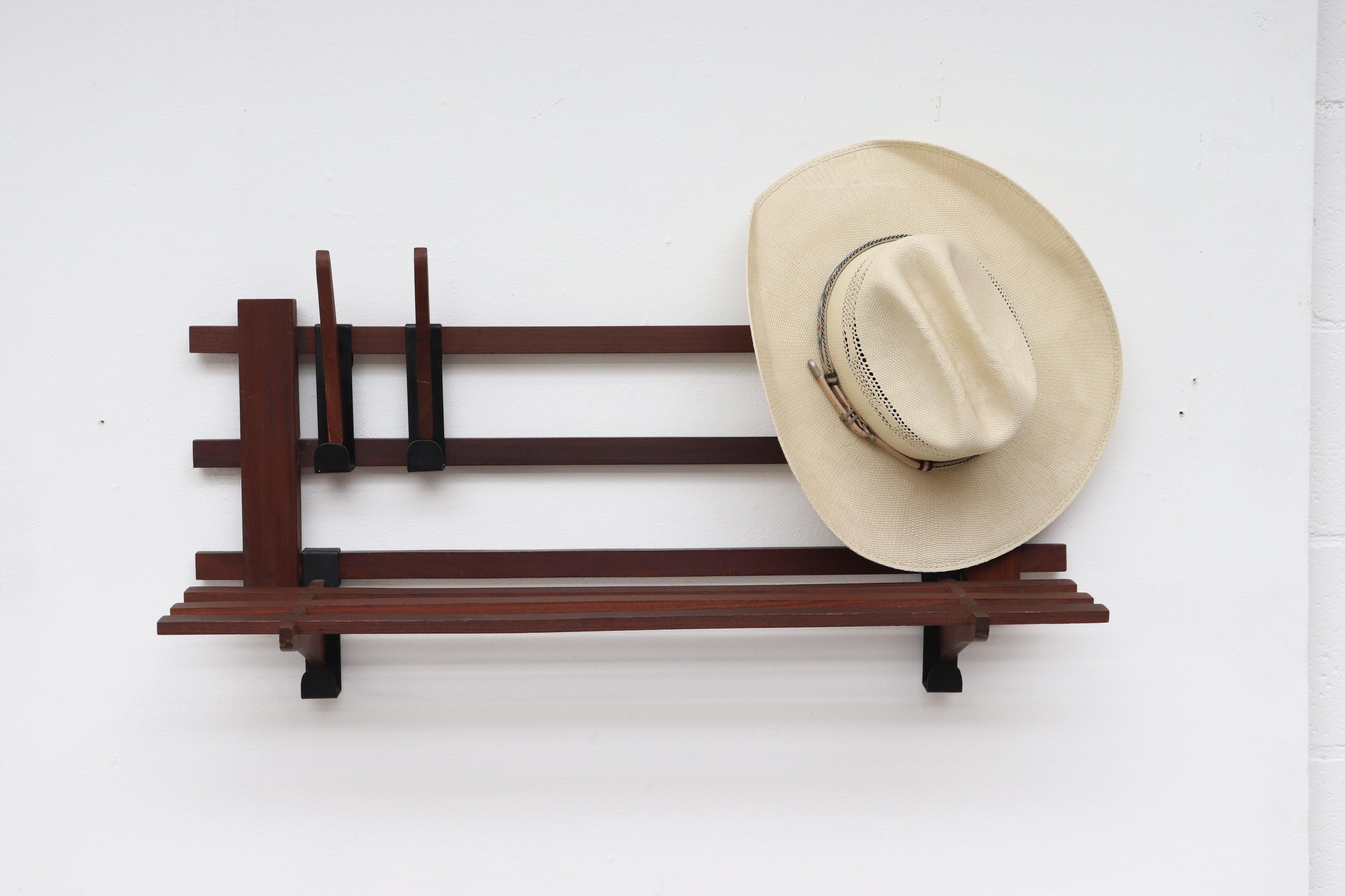 Handsome midcentury teak wall mount coat rack with removable hooks and moveable hat rack. Lightly refinished with black enameled metal accents and some visible wear.