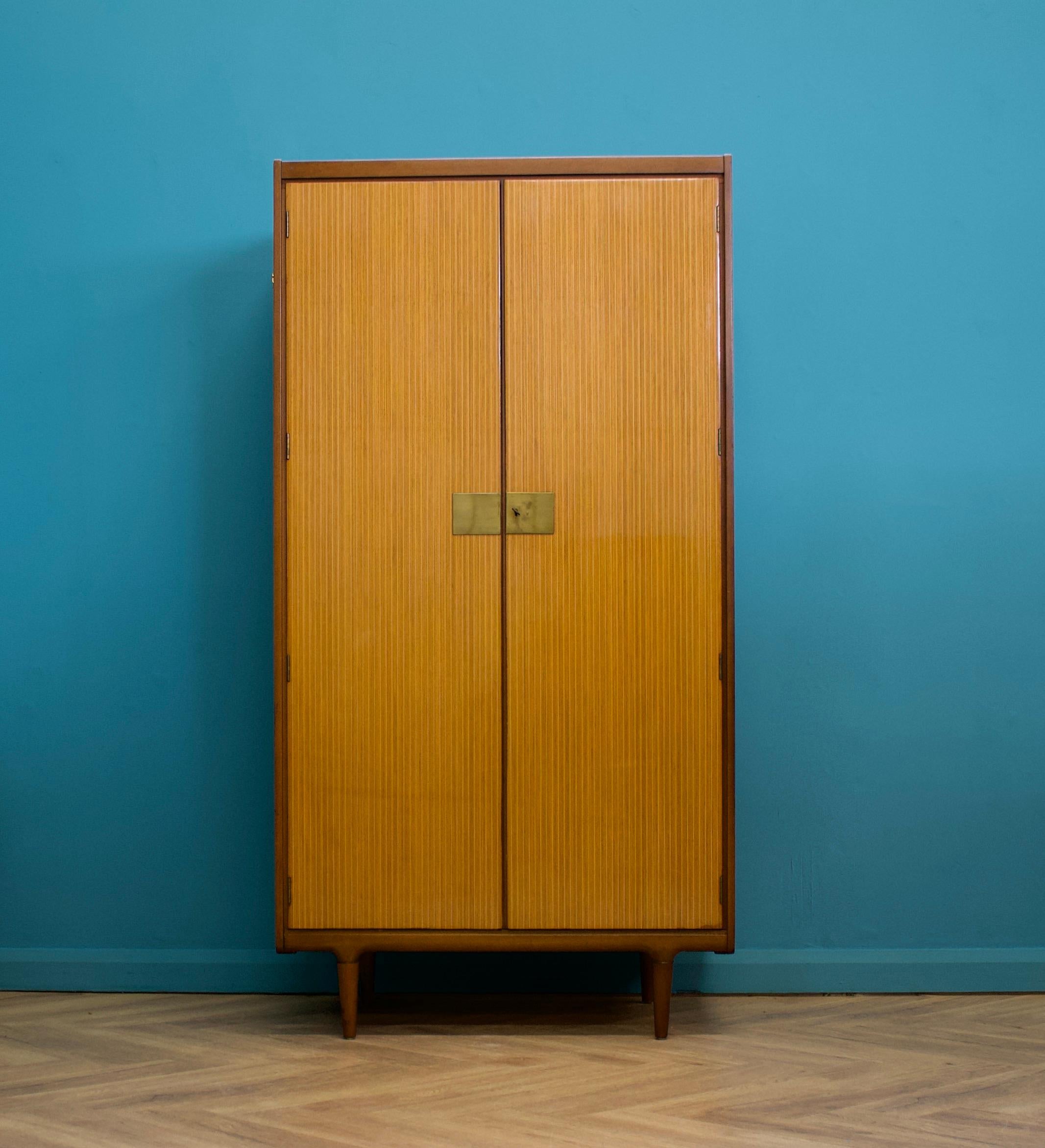 A freestanding two door teak & walnut high polish wardrobe from Wrighton -  in the Italian style
Made during the 1960s


Fitted out with a clothes rail and compartments and shelves to the other