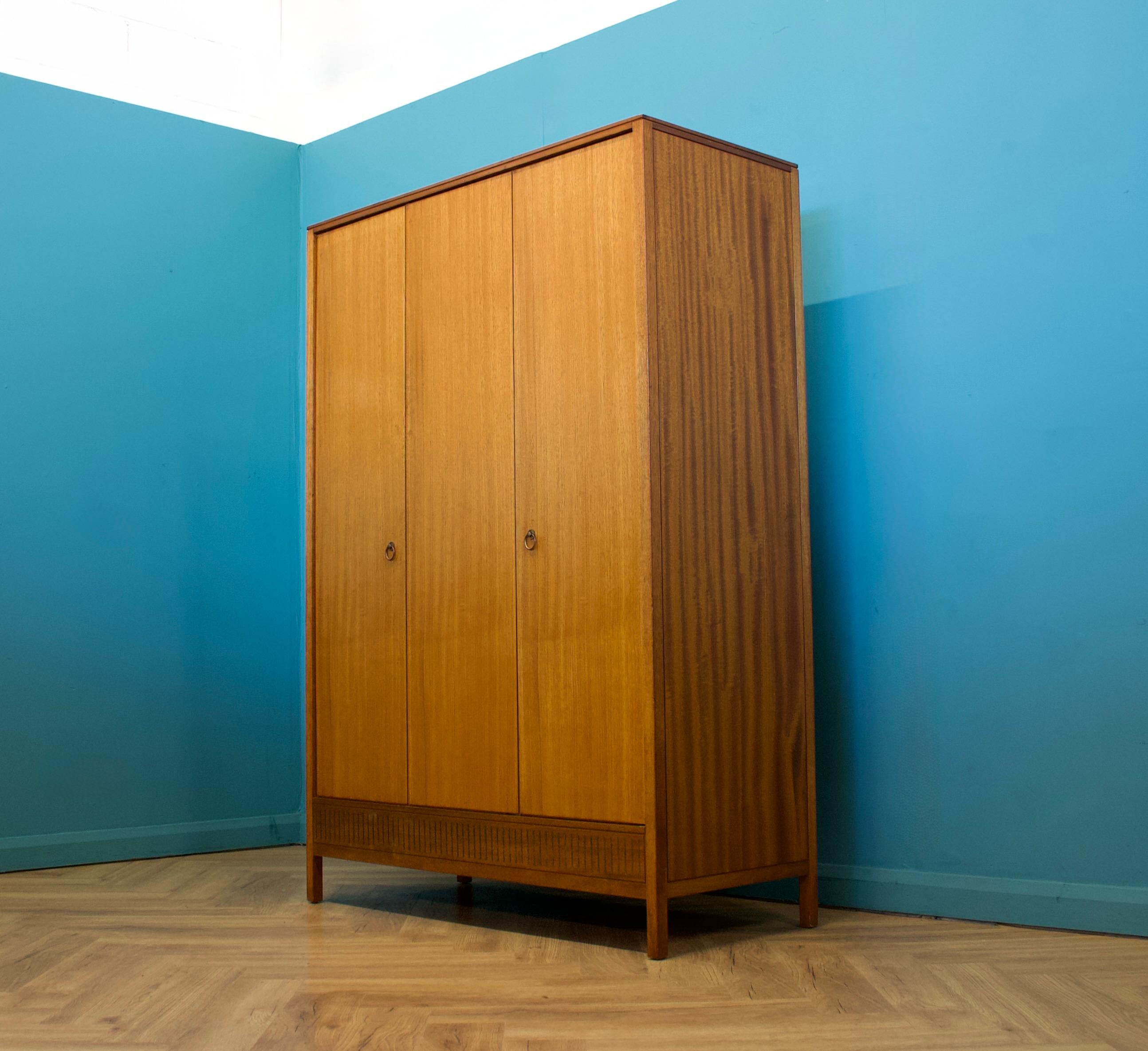 A freestanding triple door teak wardrobe designed by Austin & Ward for Loughbourgh Furniture.  These pieces were usually retailed through Heals department store.
Made during the 1960s


Fitted out with a clothes rail and a pull out storage tray to