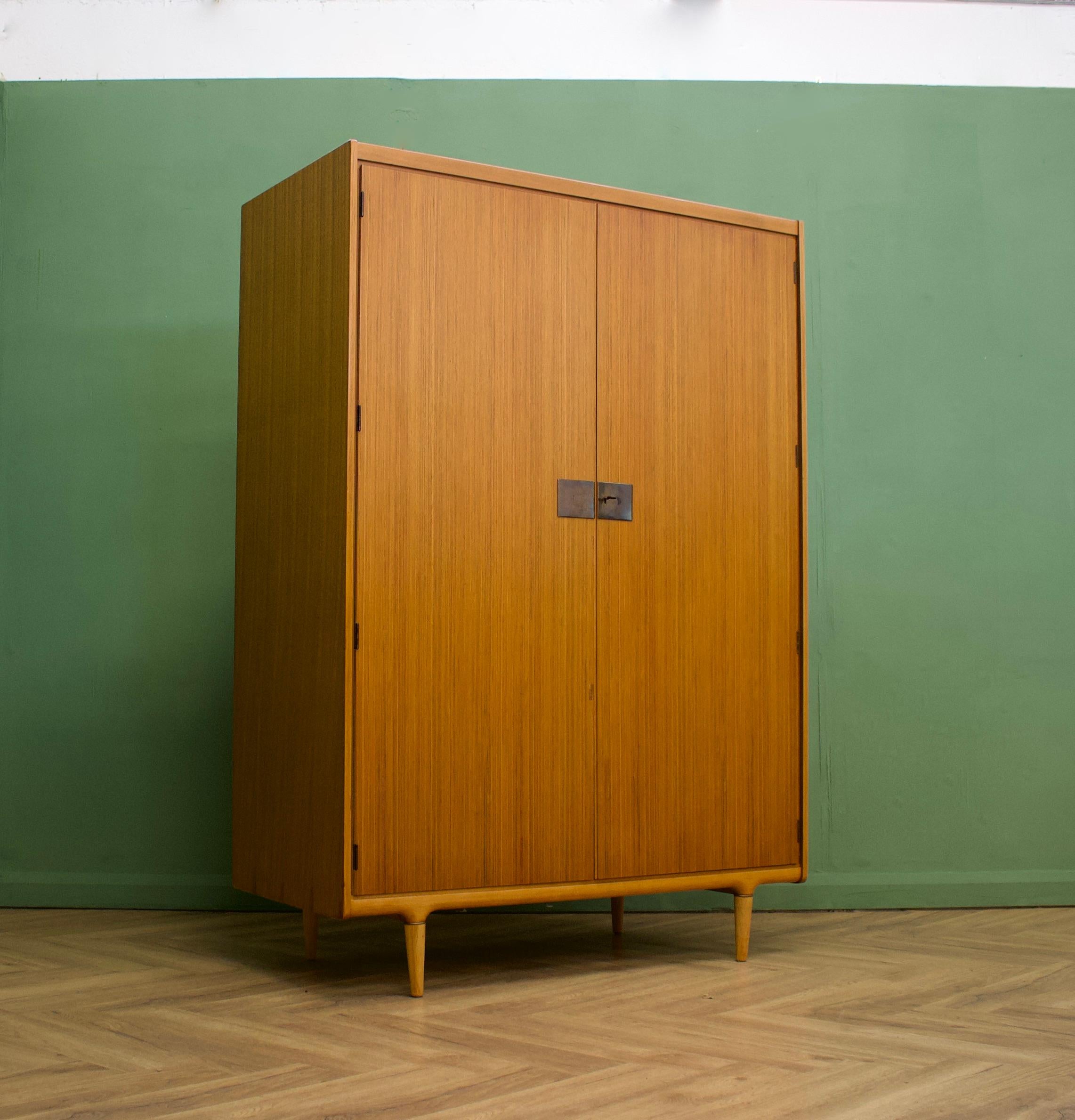 A freestanding two door teak wardrobe from Wrighton -  in the Danish modern style
Made during the 1960s


Fitted out with a clothes rail and compartments and shelves to the other


This wardrobe flat packs