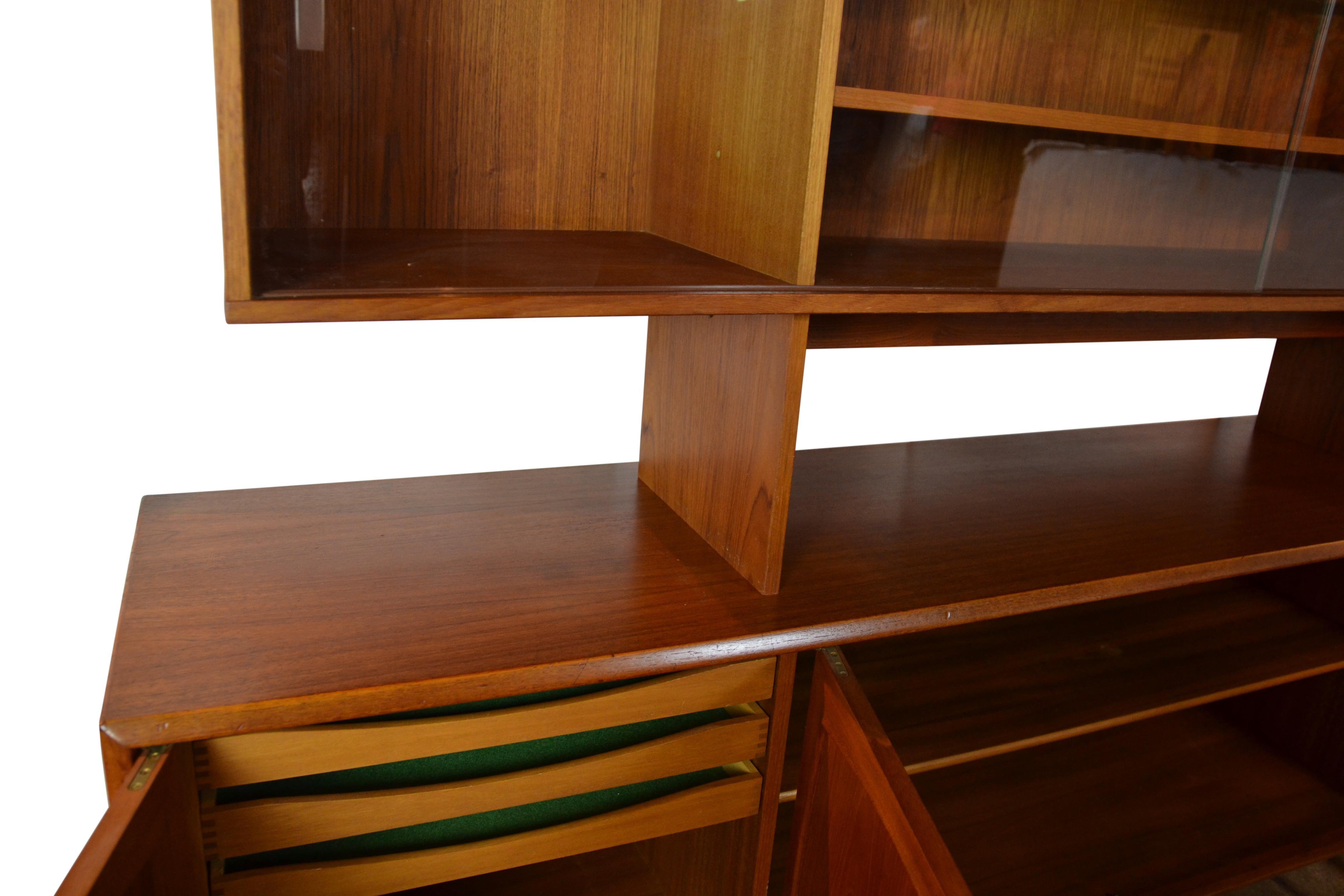 A 2 part midcentury teak-wood sideboard / buffet / bookcase with a removable top cabinet. Cupboards to the base and sliding glass doors to the top section. Small pegs hold the top in place but the top is removable.