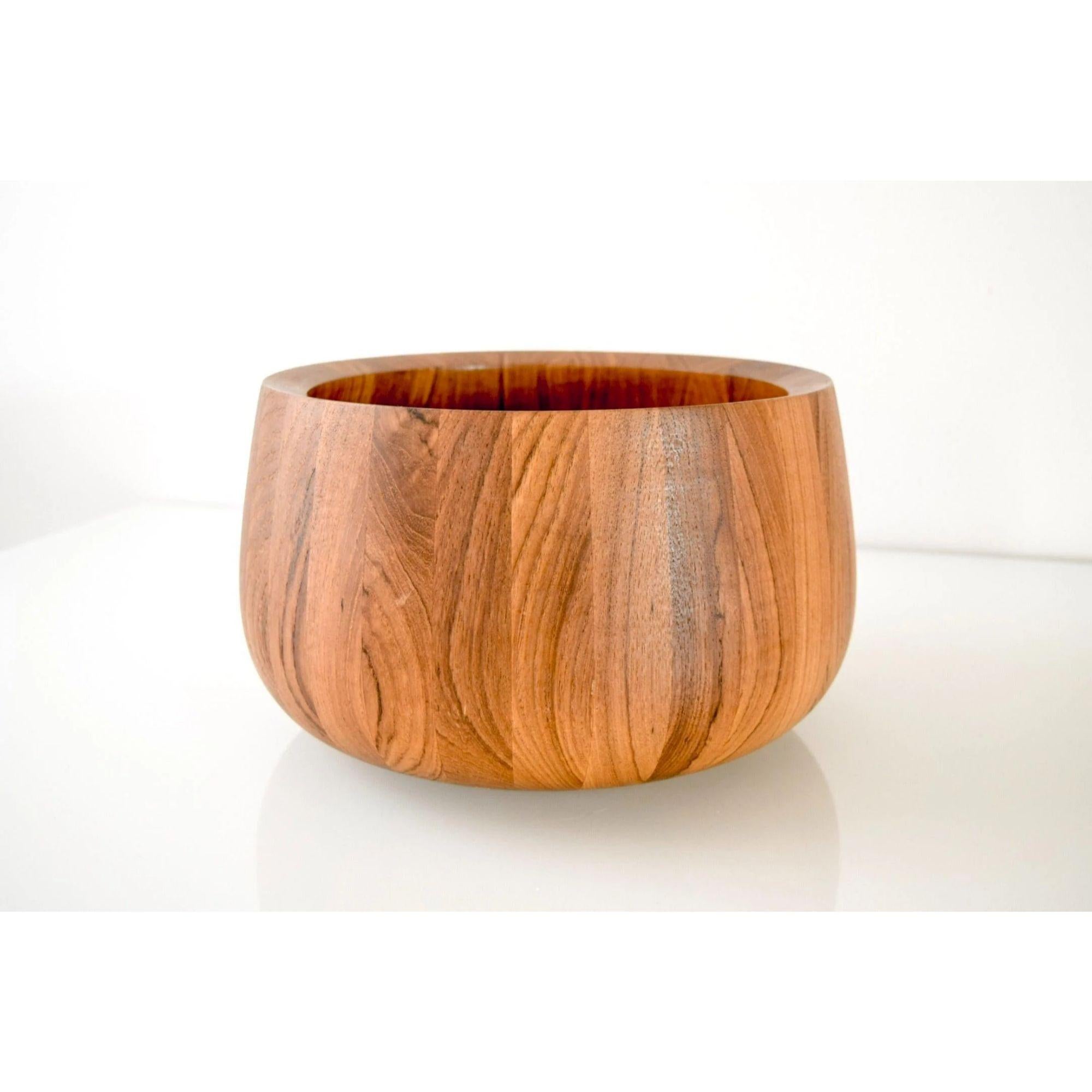 This large vintage mid-century Danish modern Dansk teak wood fruit or salad bowl is circa 1960. It is made from thick solid staved teak wood with gorgeous grain and features a simple, elegant design with tall sides that angle in slightly to create a
