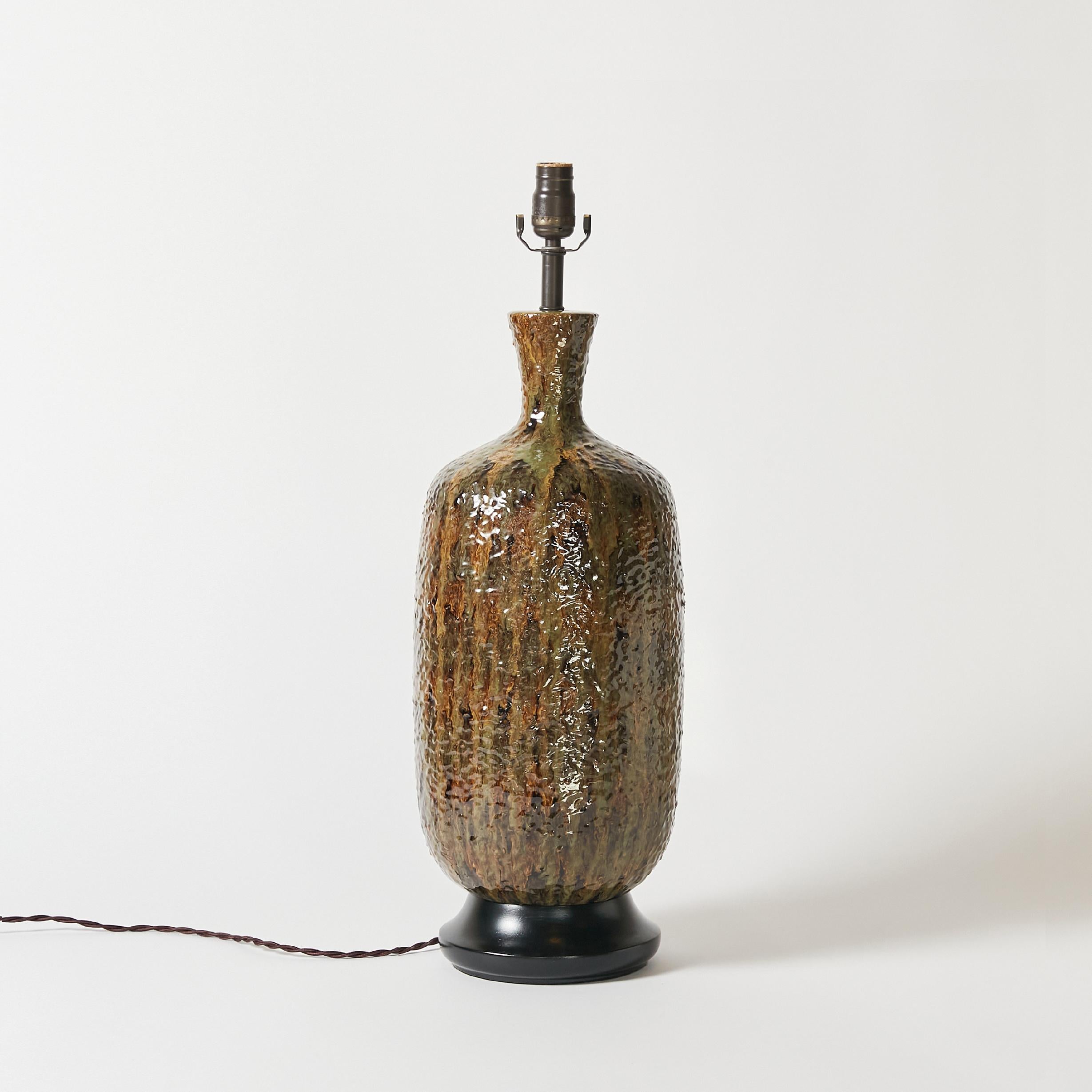 Mid century ceramic table lamp with textured glaze finish in different shades of dry green.
This item has been rewired with new hardware and braided cloth cord. This lamp does not include shade or harp.