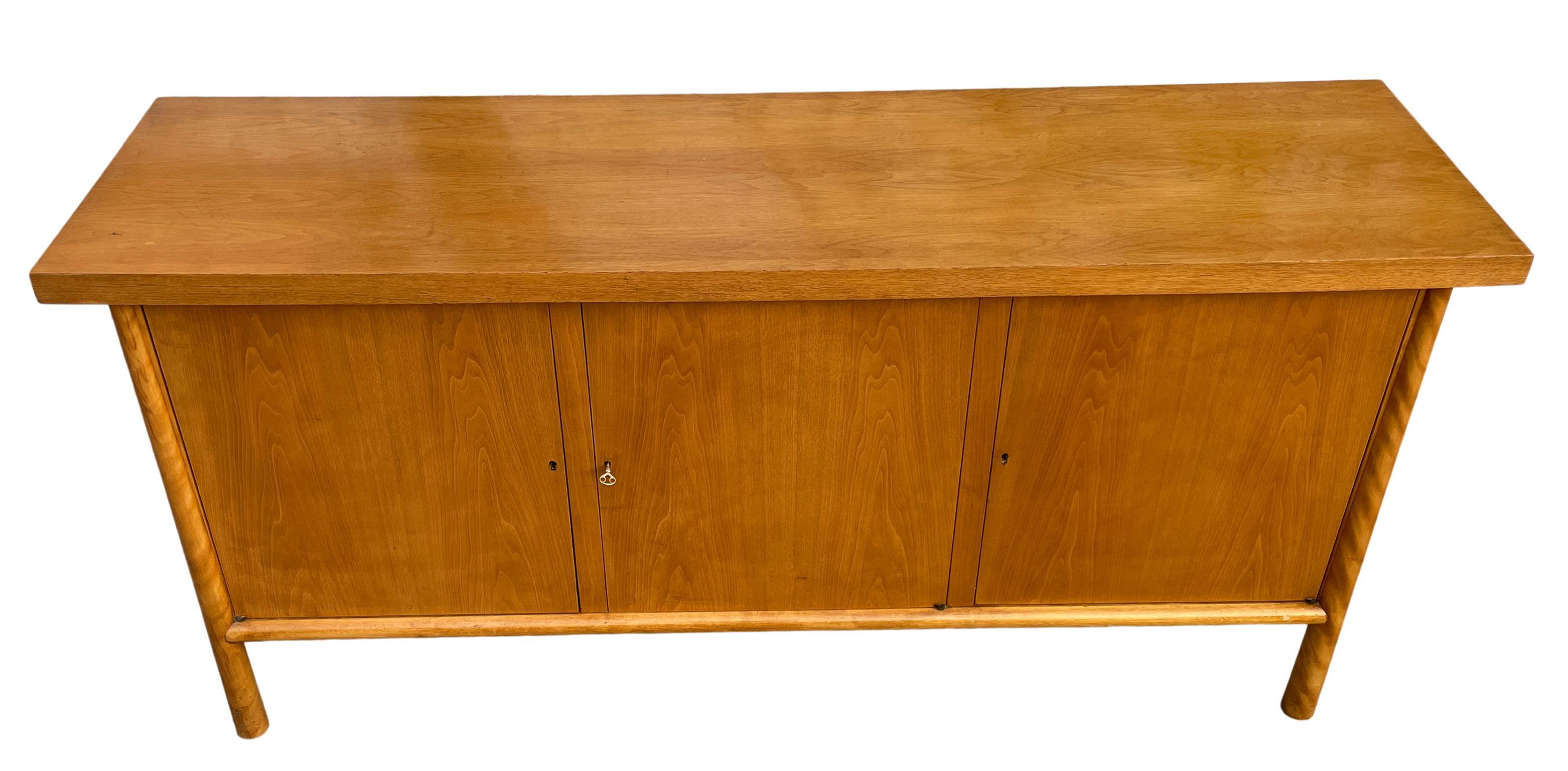 Beautiful blonde maple three door 'MING' credenza sideboard with oversized surface and sculptural, tapered legs designed by Robsjohn-Gibbings for Widdicomb Circa 1950. The left and right cabinet doors open to reveal adjustable shelves (3 adjustable