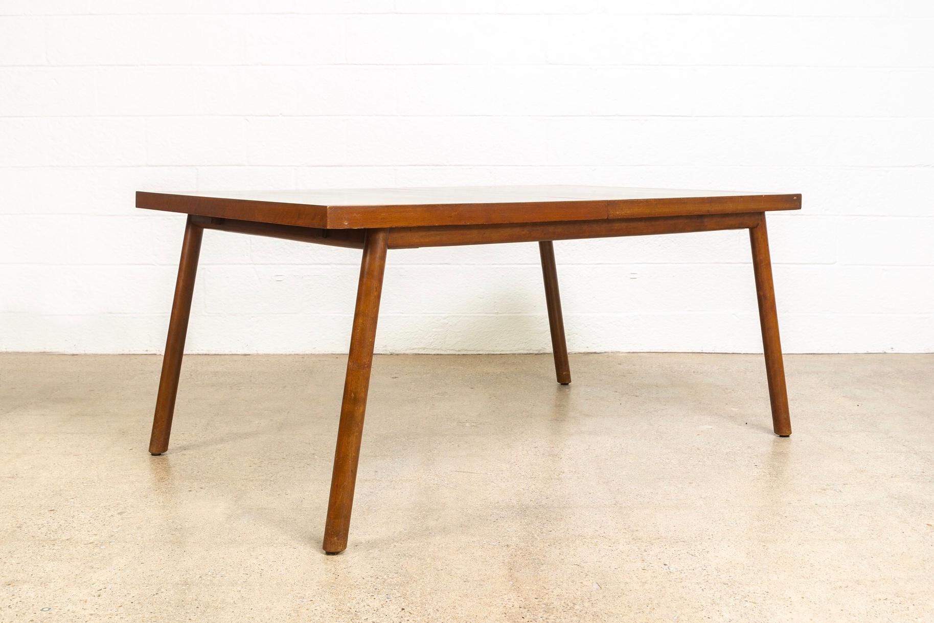 This vintage Mid-Century Modern dining table made in 1952 was designed by British-born T.H. Robsjohn-Gibbings and manufactured by Widdicomb. The table has an elegant Minimalist aesthetic and a clean, unimposing, rectilinear design featuring round