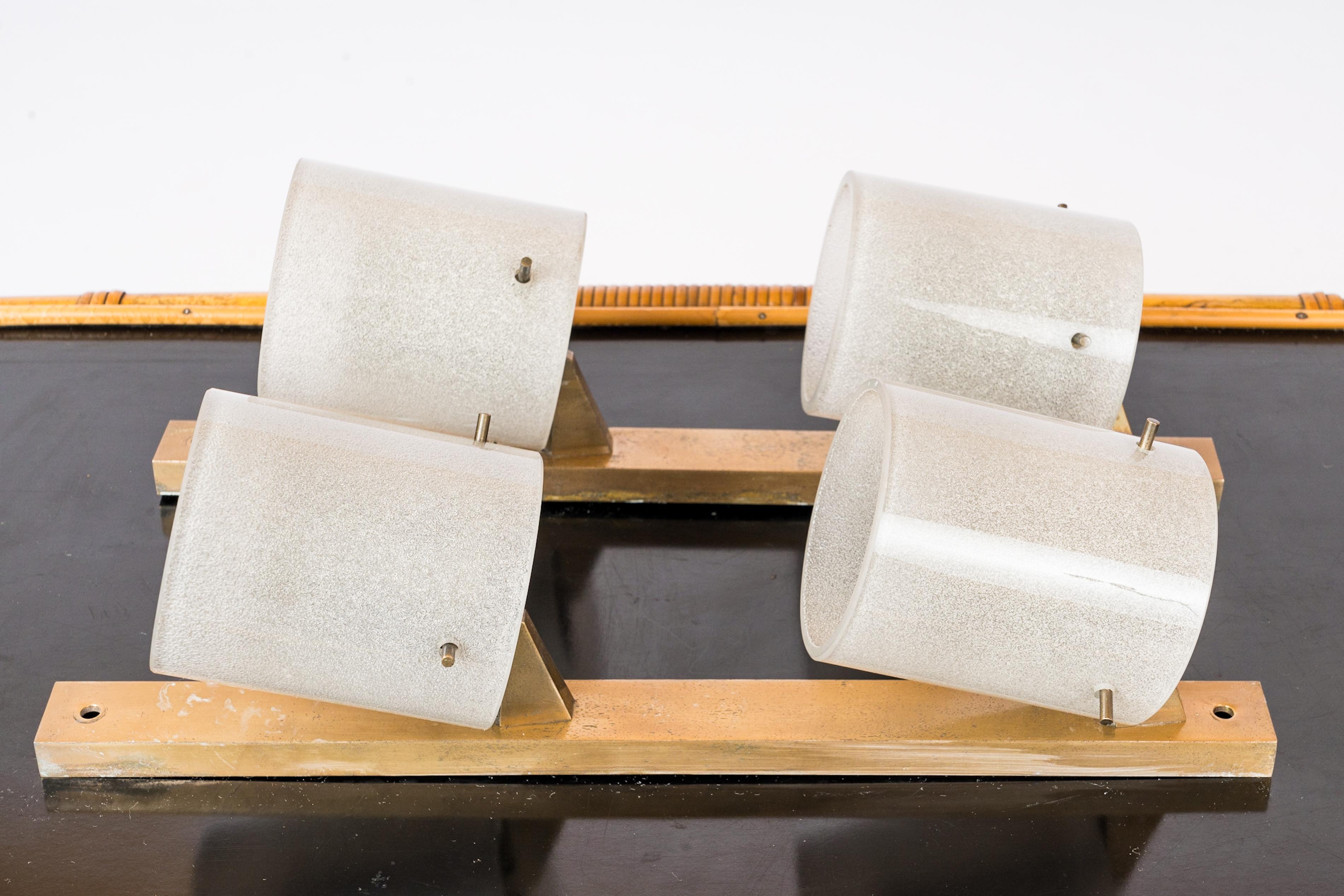 Paire d'appliques modernistes en laiton et verre épais du milieu du siècle dans le style de Stilnovo. La surface intérieure des abat-jour en verre est texturée. Ils sont maintenus à la structure en laiton par trois pièces en laiton vissées. Les