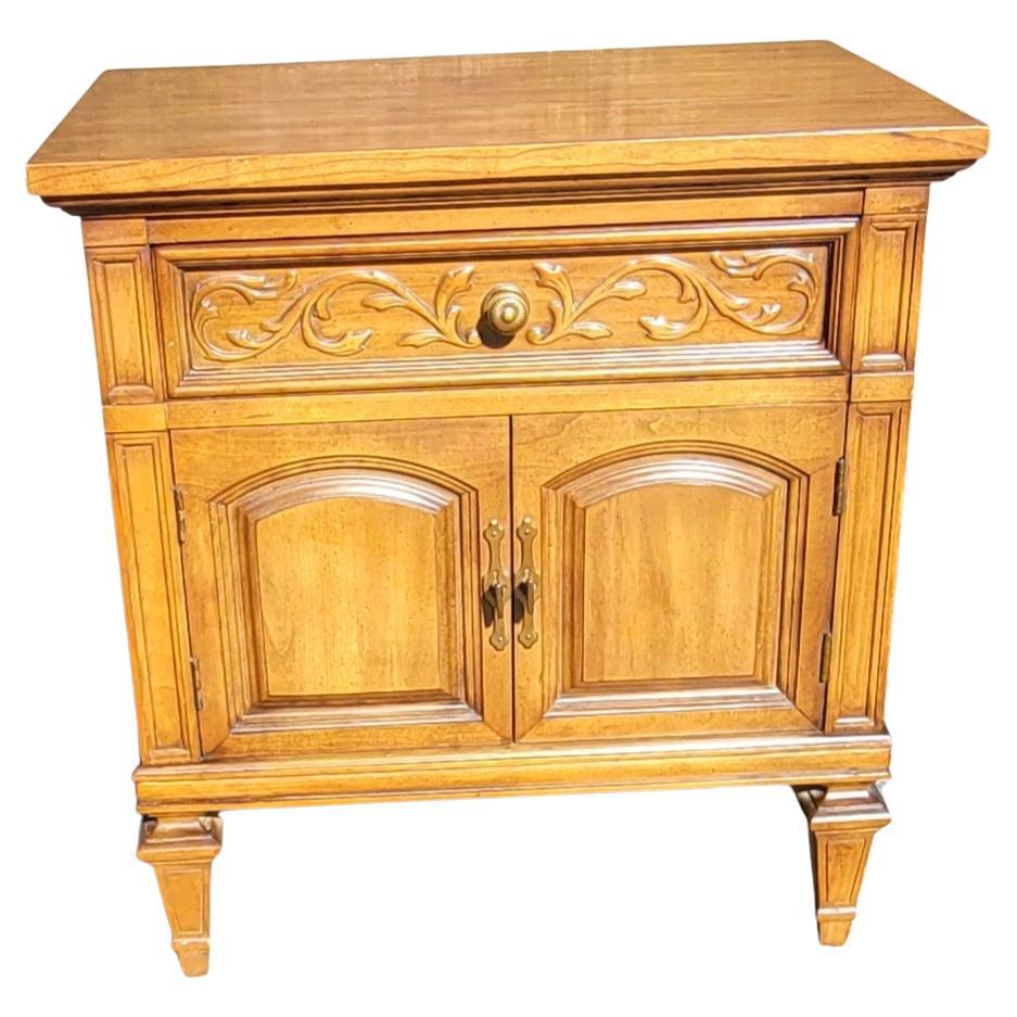 A beautiful pair of Thomasville Neoclassical Style Fruitwood bedside tables in good vintage condition. Feature one drawer, two French paneled doors. Beautiful Carved flowers along the drawer door. Measure 24