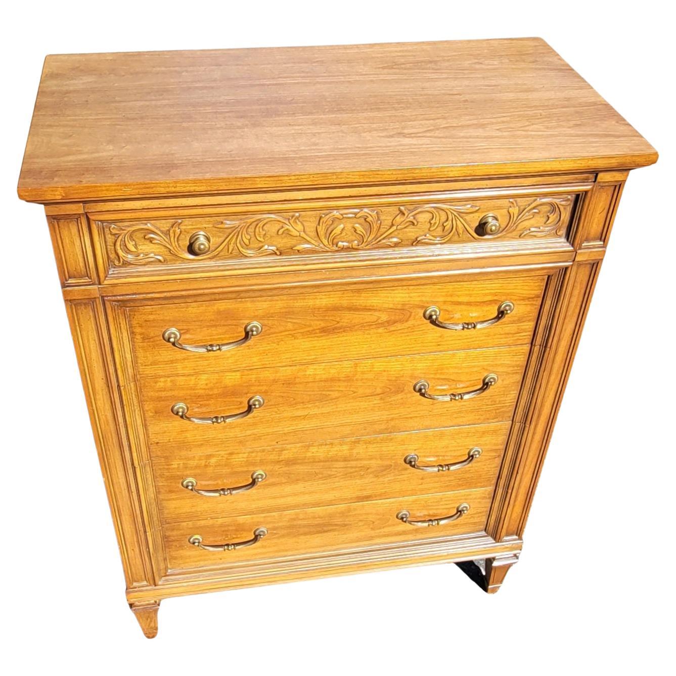 A beautiful pair of Thomasville Neoclassical Style Fruitwood chest of drawers in good vintage condition. Features 5  dovetailed drawers with original heavy duty drawer pulls and knobs, top drawer flanked with skillfully carved flowers throughout..