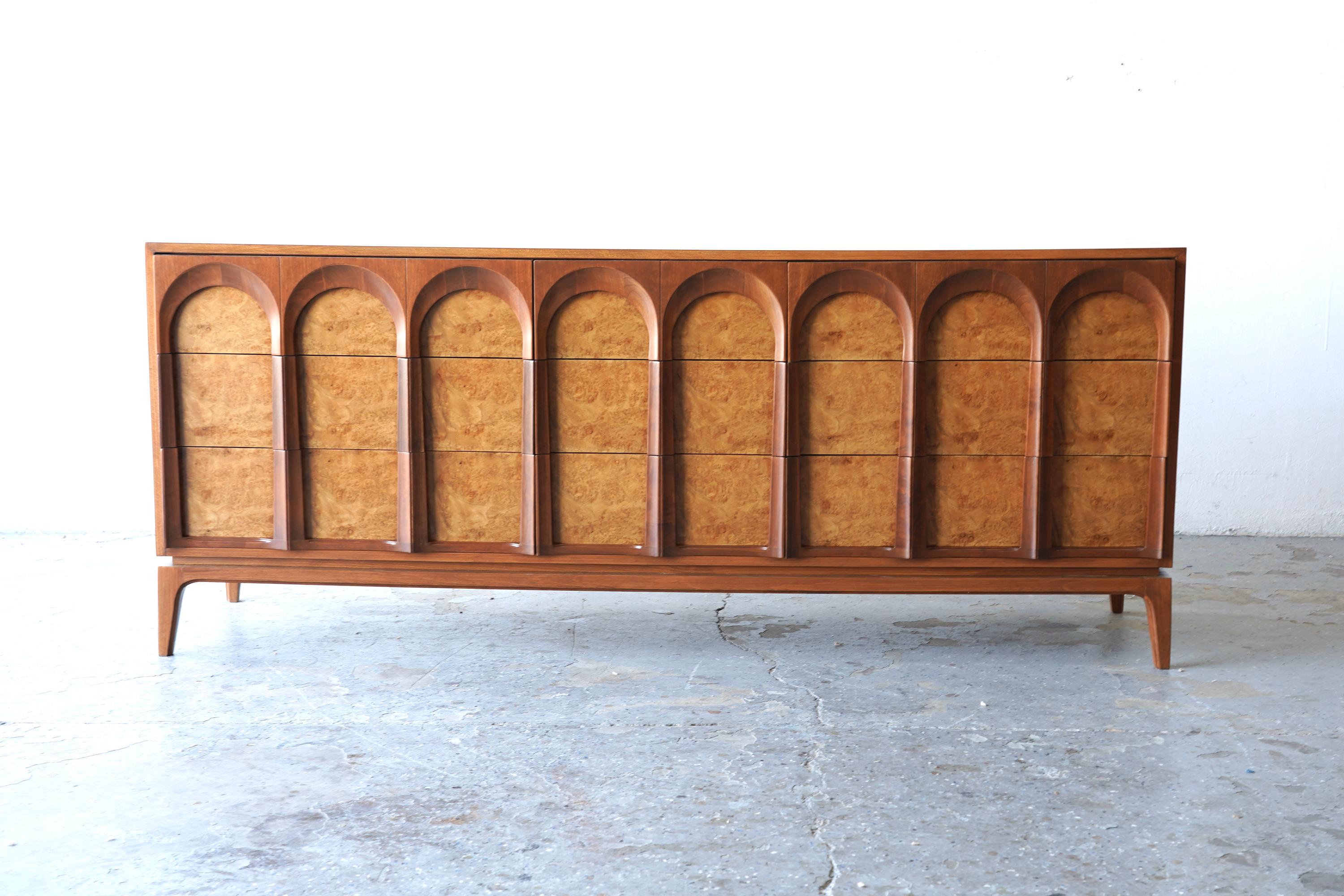 The 'Arched' series by Thomasville showcases exceptional hardwood construction, featuring exquisite burlwood veneer Has been professionally refinished. It includes  nine dovetailed drawers with distinctive arched fronts and elegant tall tapered