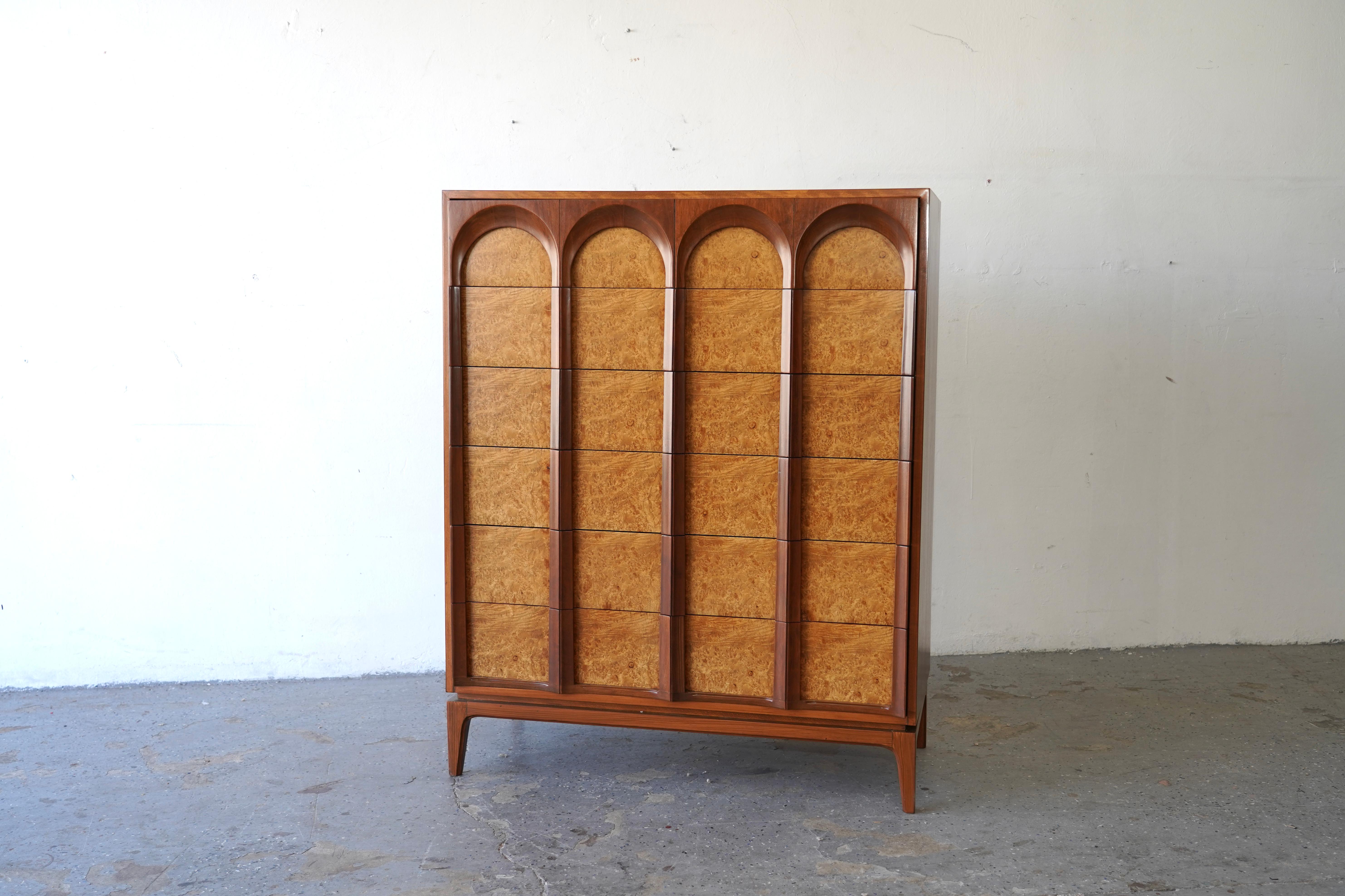 The 'Arched' series by Thomasville showcases exceptional hardwood construction, featuring exquisite burlwood veneer Has been professionally refinished. It includes six dovetailed drawers with distinctive arched fronts and elegant tall tapered