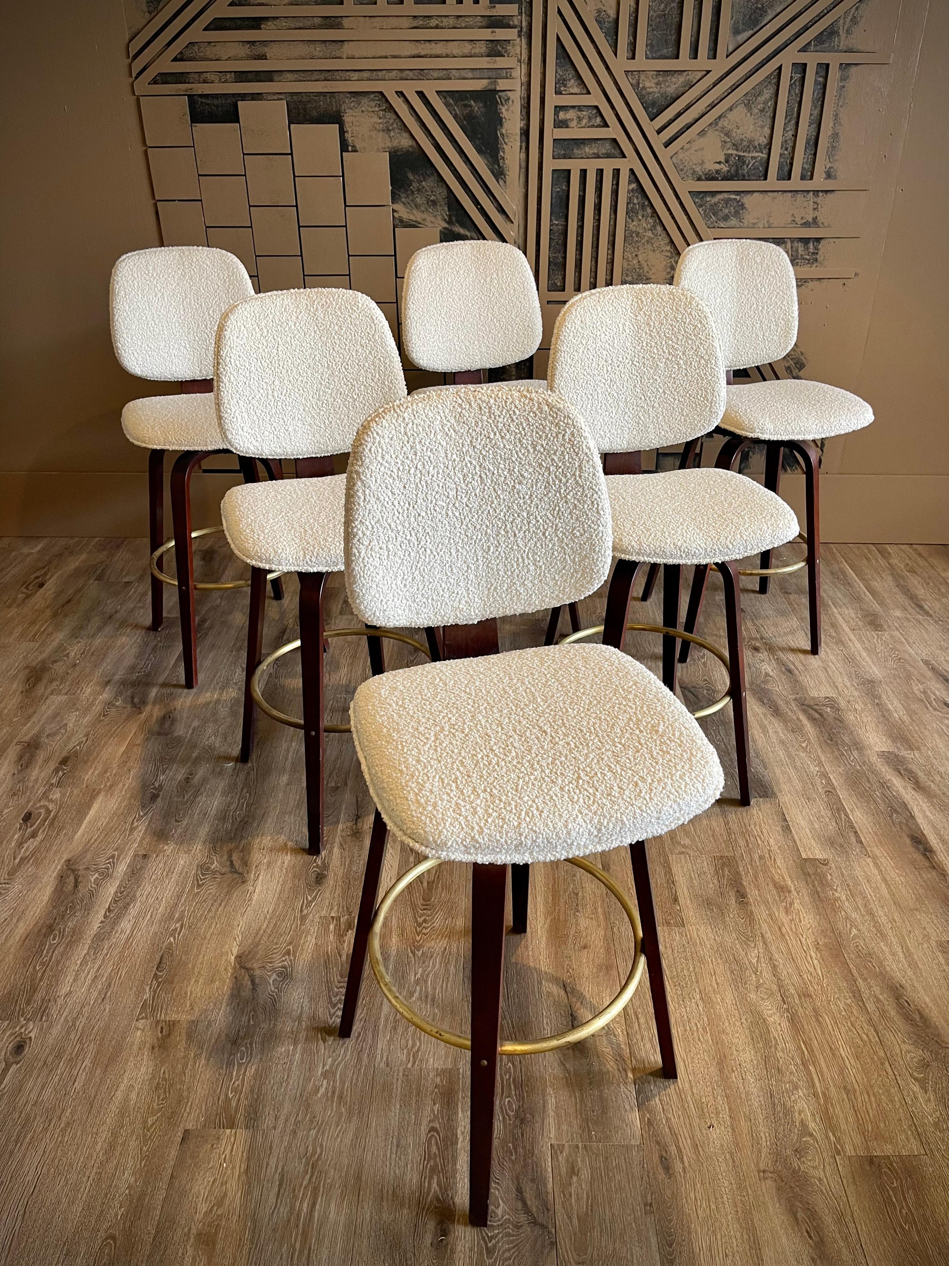 Introducing a stunning set of six Thonet swivel barstools, wonderfully maintained and boasting sleek walnut construction and brass foot rail accents. Revitalized with creamy off-white boucle upholstery, these barstools exude both luxury and comfort.