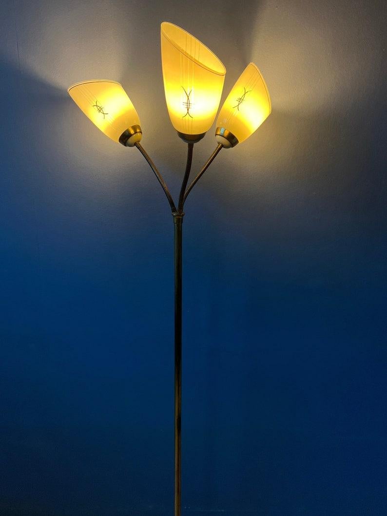 Three-armed 50s floor lamp with three glass shades and golden base elements. The three arms are flexible and can be moved separately in any direction. The foot switch allows you to turn on the shades simultaneously or separately. The lamp requires