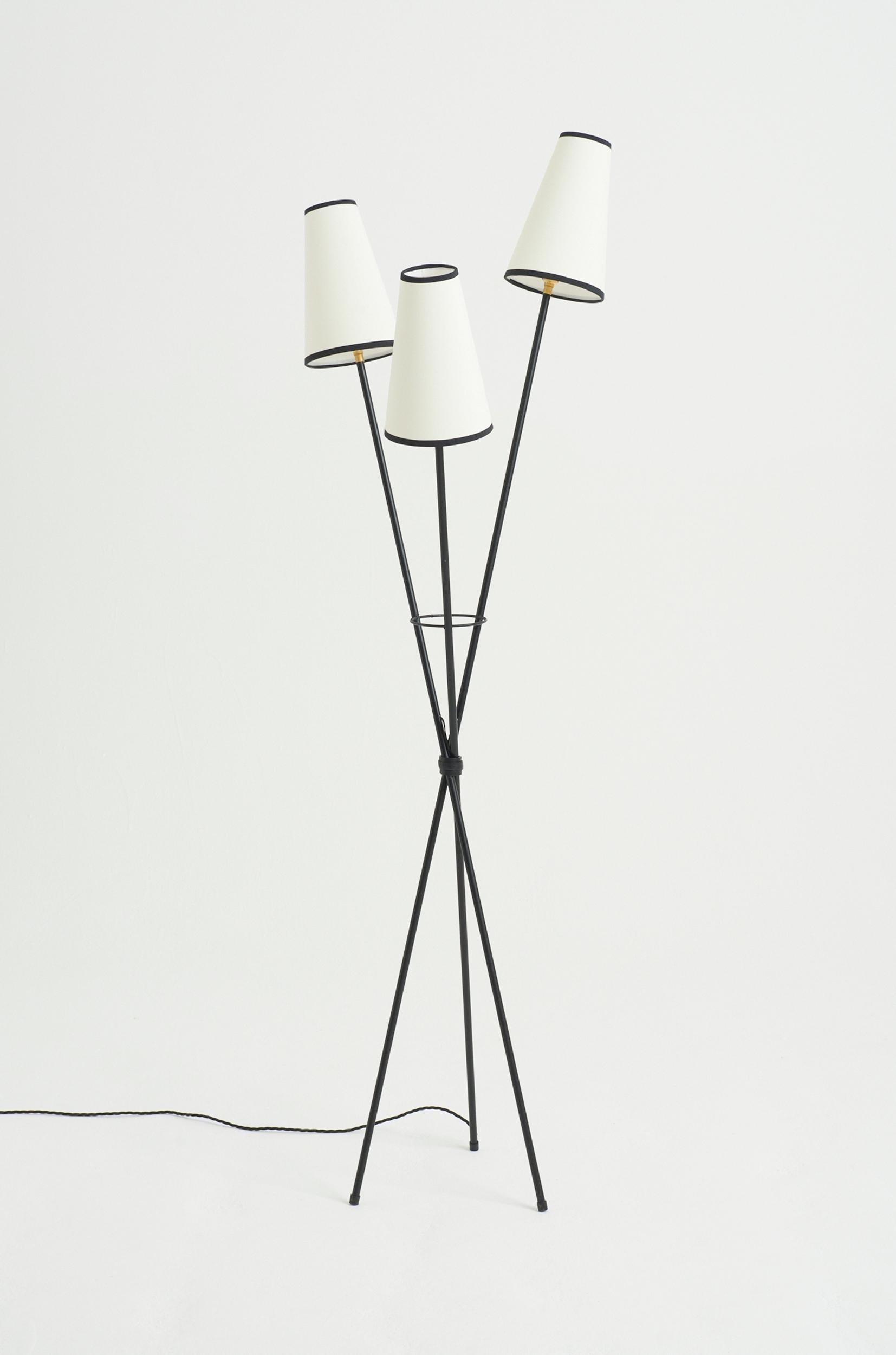 A three armed black enamelled iron floor lamp, with bespoke shades
France, mid 20th Century
159 cm high by 46 cm wide by 46 cm depth