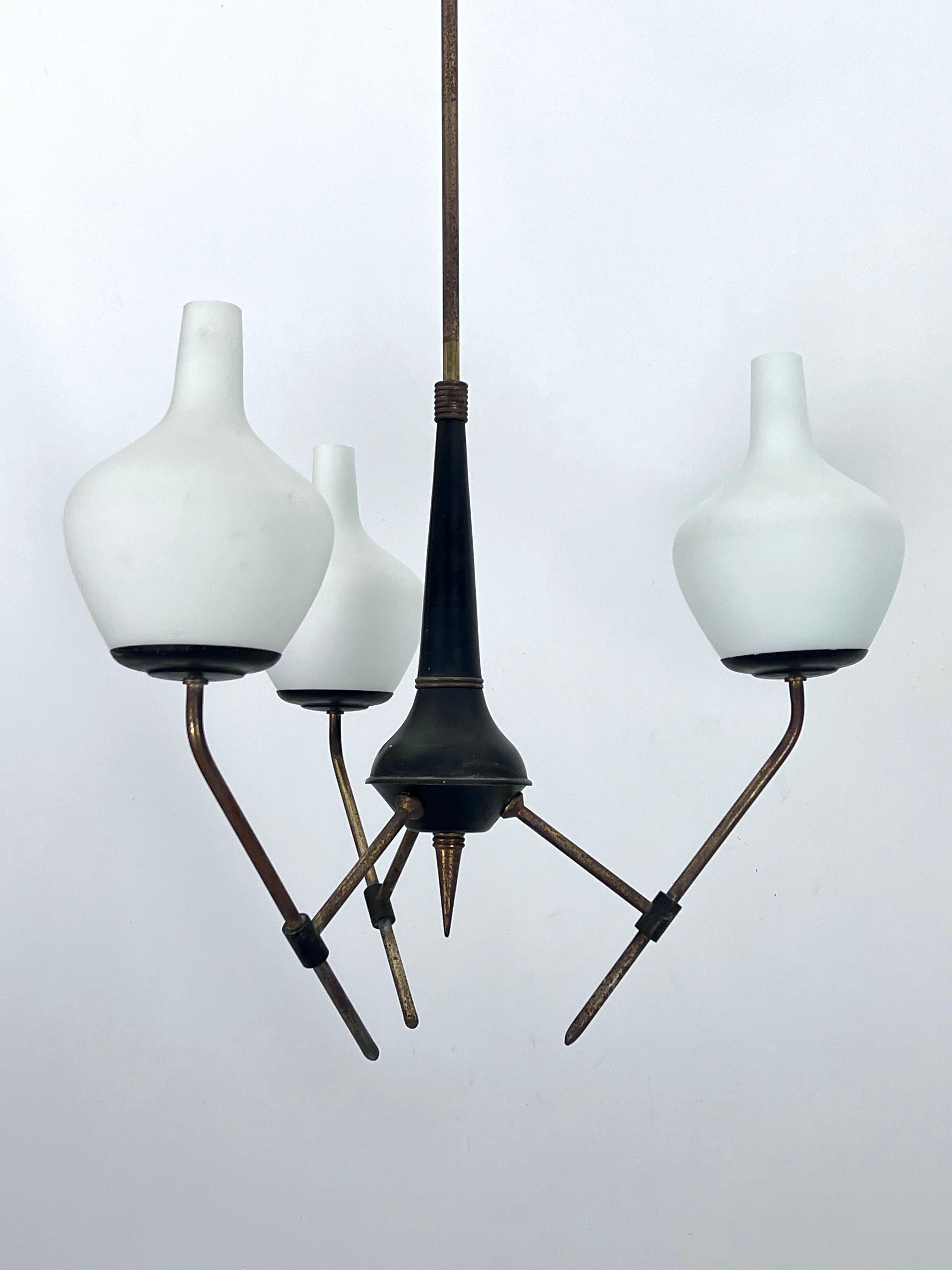 Mid-century three light chandelier in brass and black lacquered metal with opaline glasses. Fair vintage condition with oxidation on the brass and small chips on two glasses as shown in pictures. It mounts three sockets for E14 bulbs. Full working