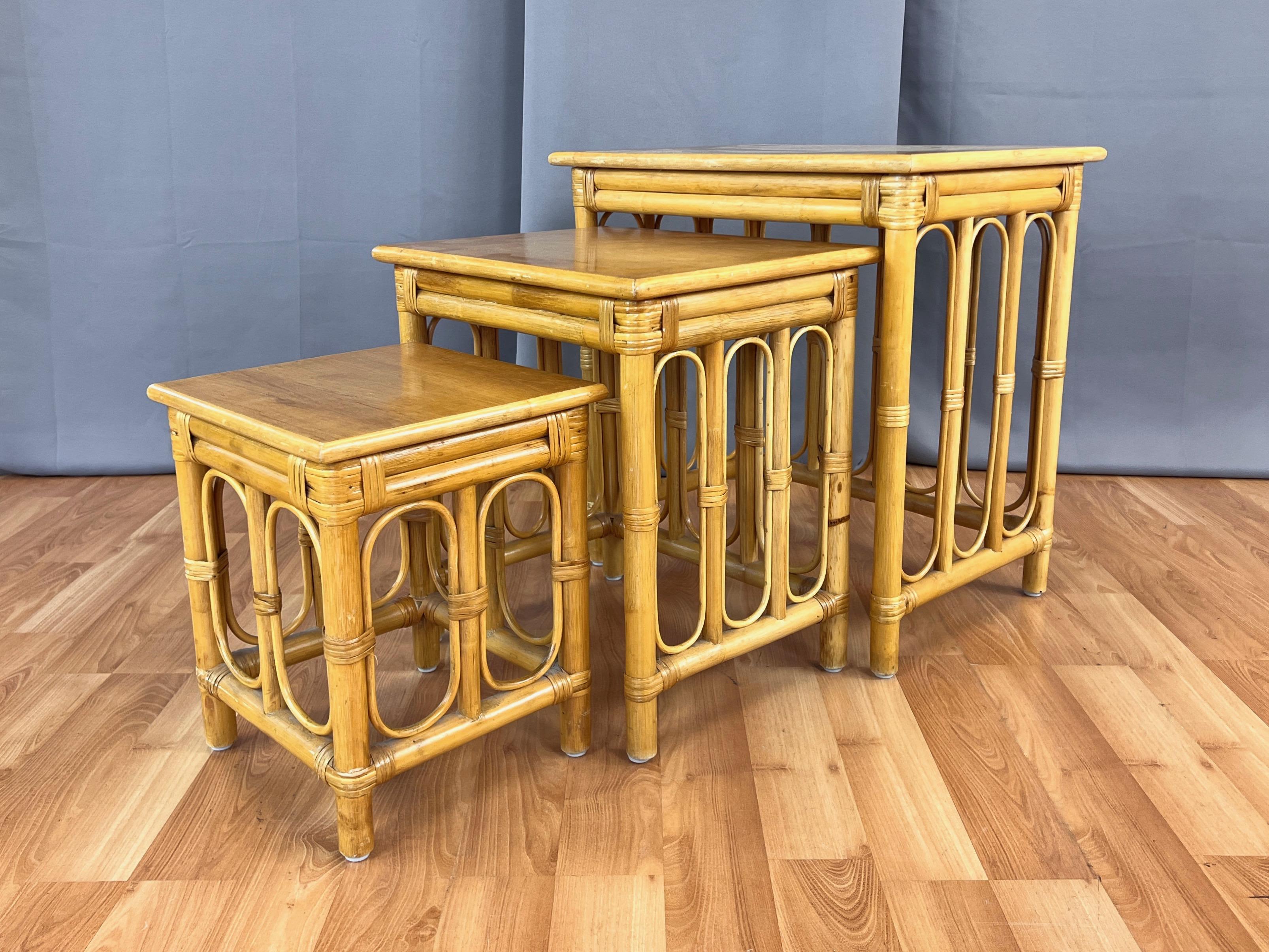 Très bel ensemble de tables gigognes en rotin des années 1950, composé de trois pièces.

Les tables sont dotées d'un cadre en rotin naturel et d'accents en cannage sur l'ensemble de la table. Les éléments en rotin fin en forme d'hippodrome entre les