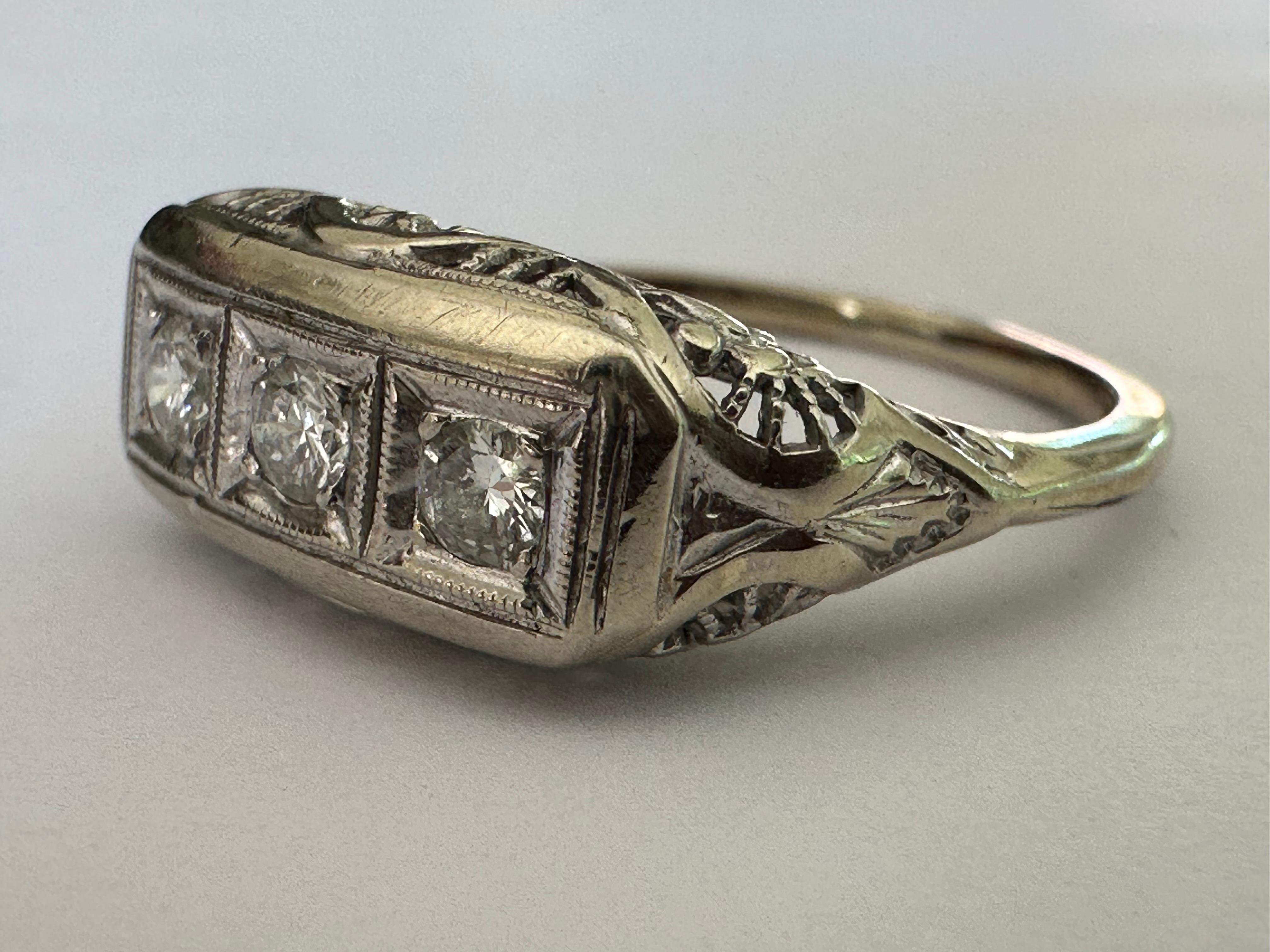 This mid-century gem crafted in the 1960s is designed around a trio of round brilliant-cut diamonds totaling approximately 0.15 carat, F color VS clarity, accented with fine filigree. Set in 14K white gold. 
