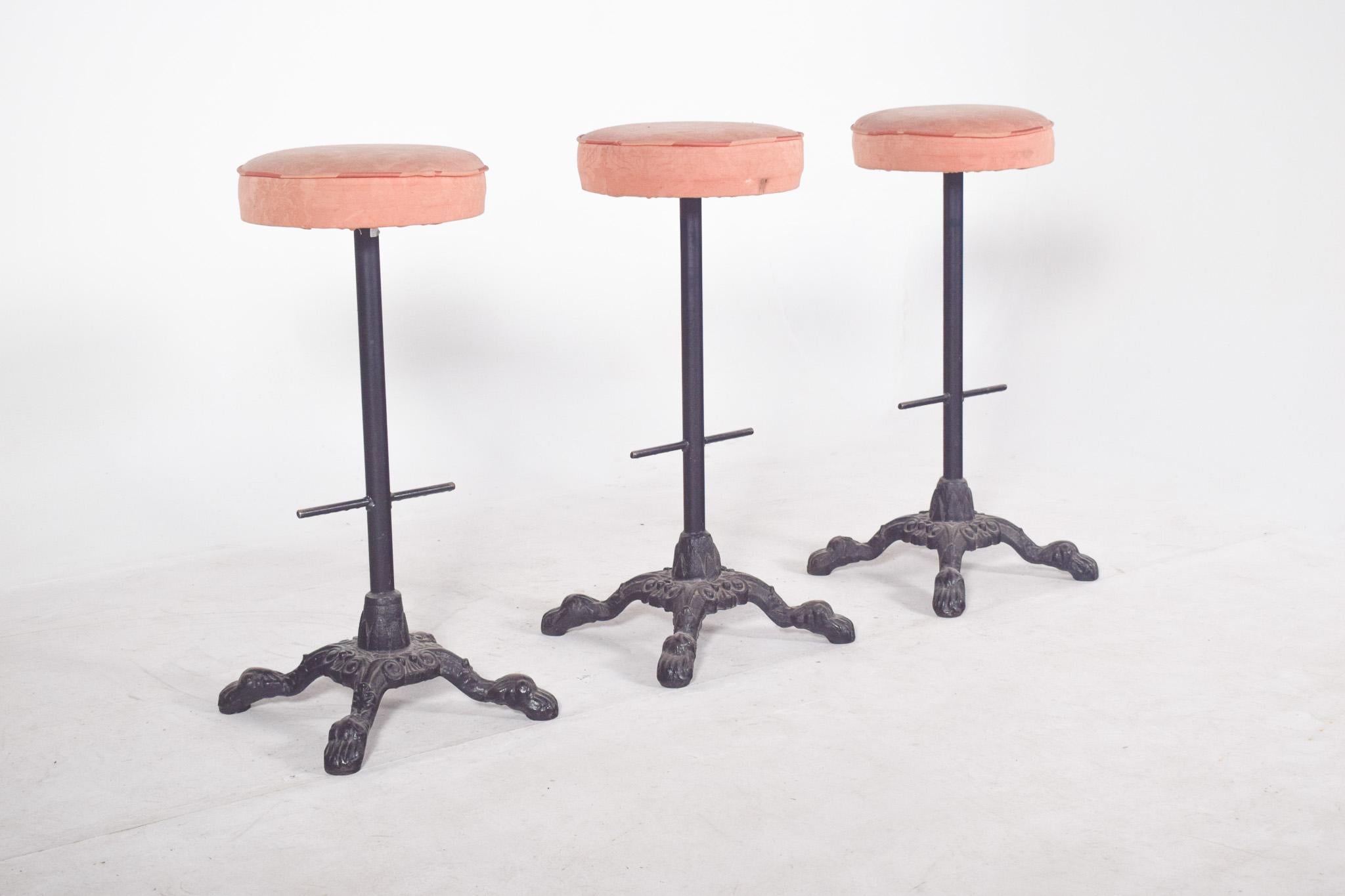 Trois tabourets de bar hauts en fer. Idéal pour les comptoirs de bar, les cafés ou les cuisines avec îlots. Chaque tabouret est doté d'une base robuste en fonte ornée, avec quatre pieds incurvés en forme de griffe qui garantissent la stabilité et un