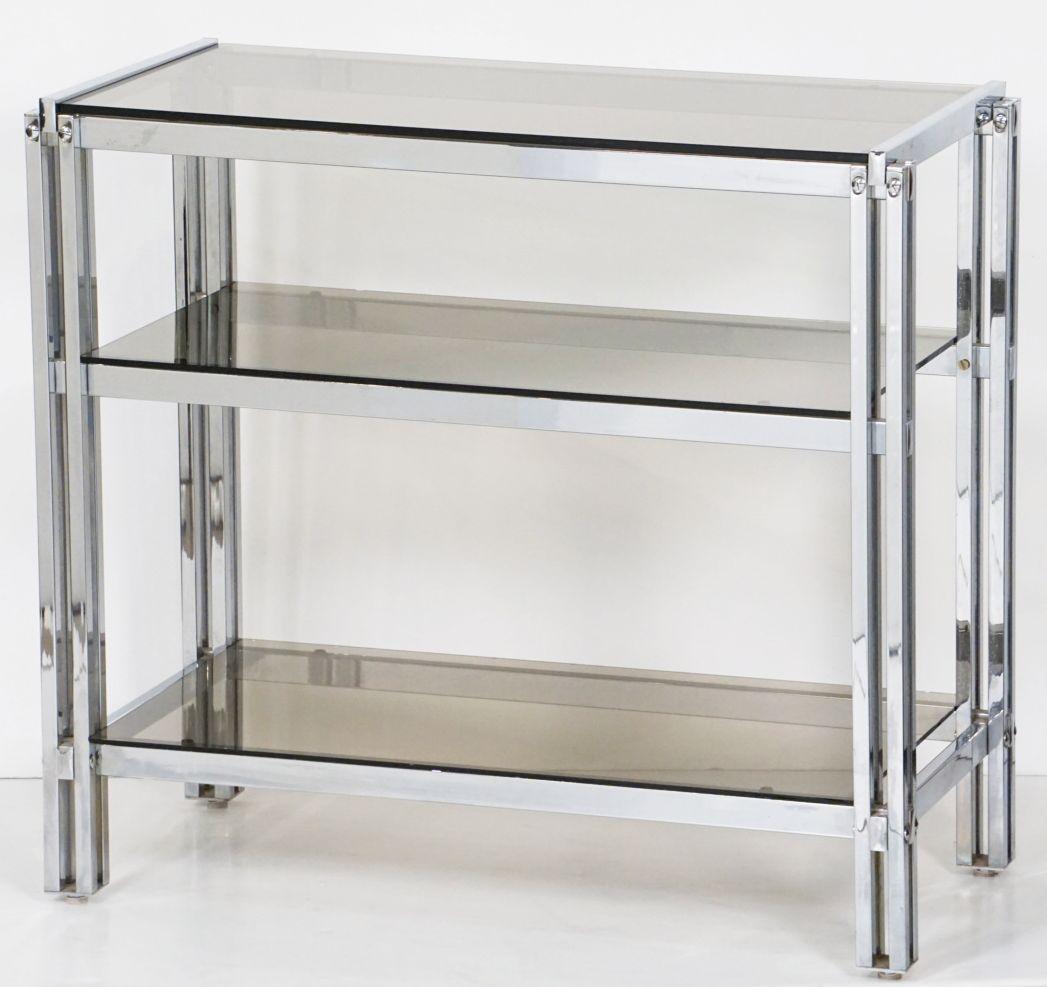 A fine French three-tiered console table, featuring a rectangular frame with a Modernist design of interlocking chromed metal with three shelves of smoked glass.