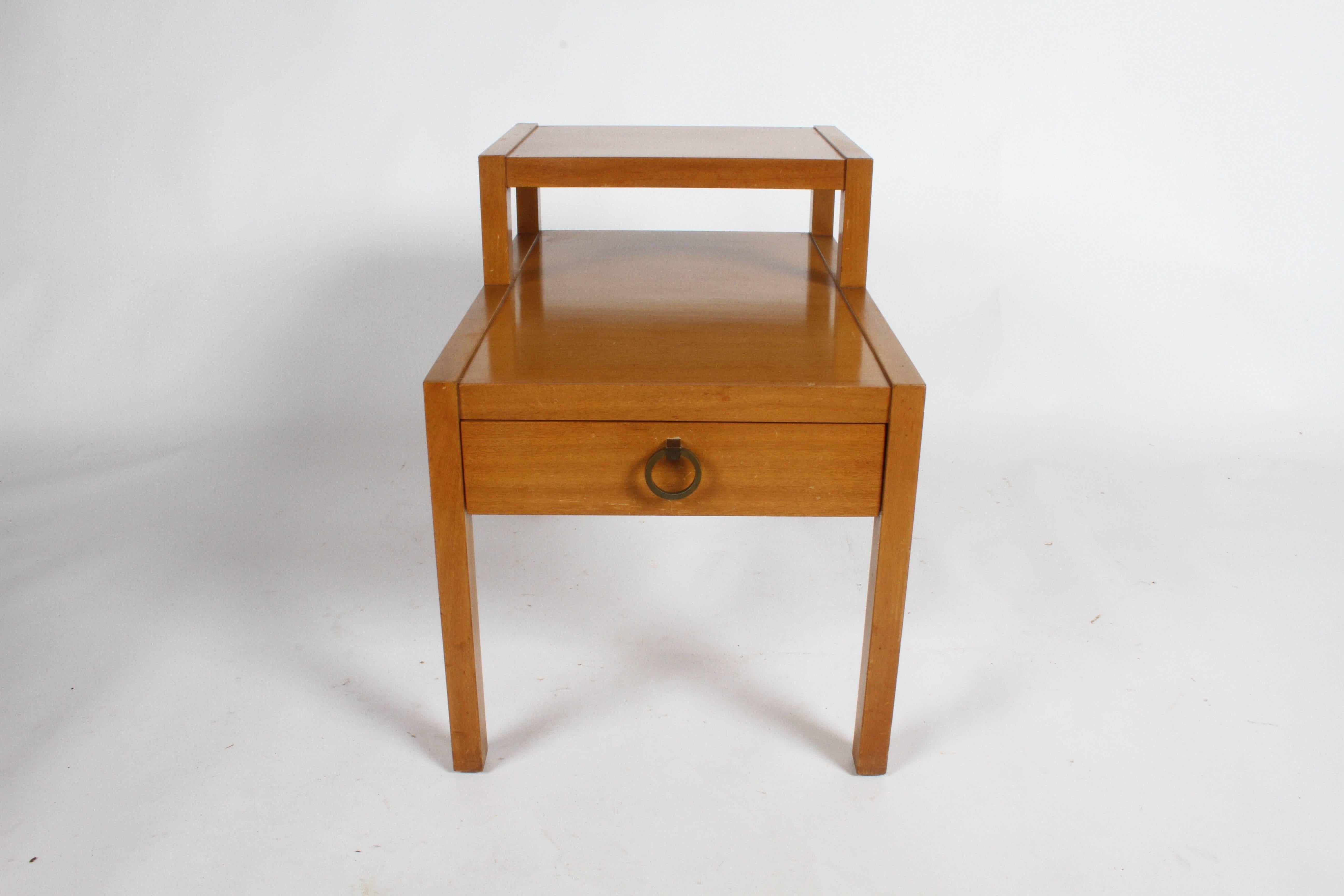 Table d'appoint en acajou à gradins ou à étages des années 1950, avec tiroir et tirette en laiton de style asiatique. Présentée dans sa finition blonde d'origine, elle présente des traces d'usure. Peut être remis en état moyennant un supplément de