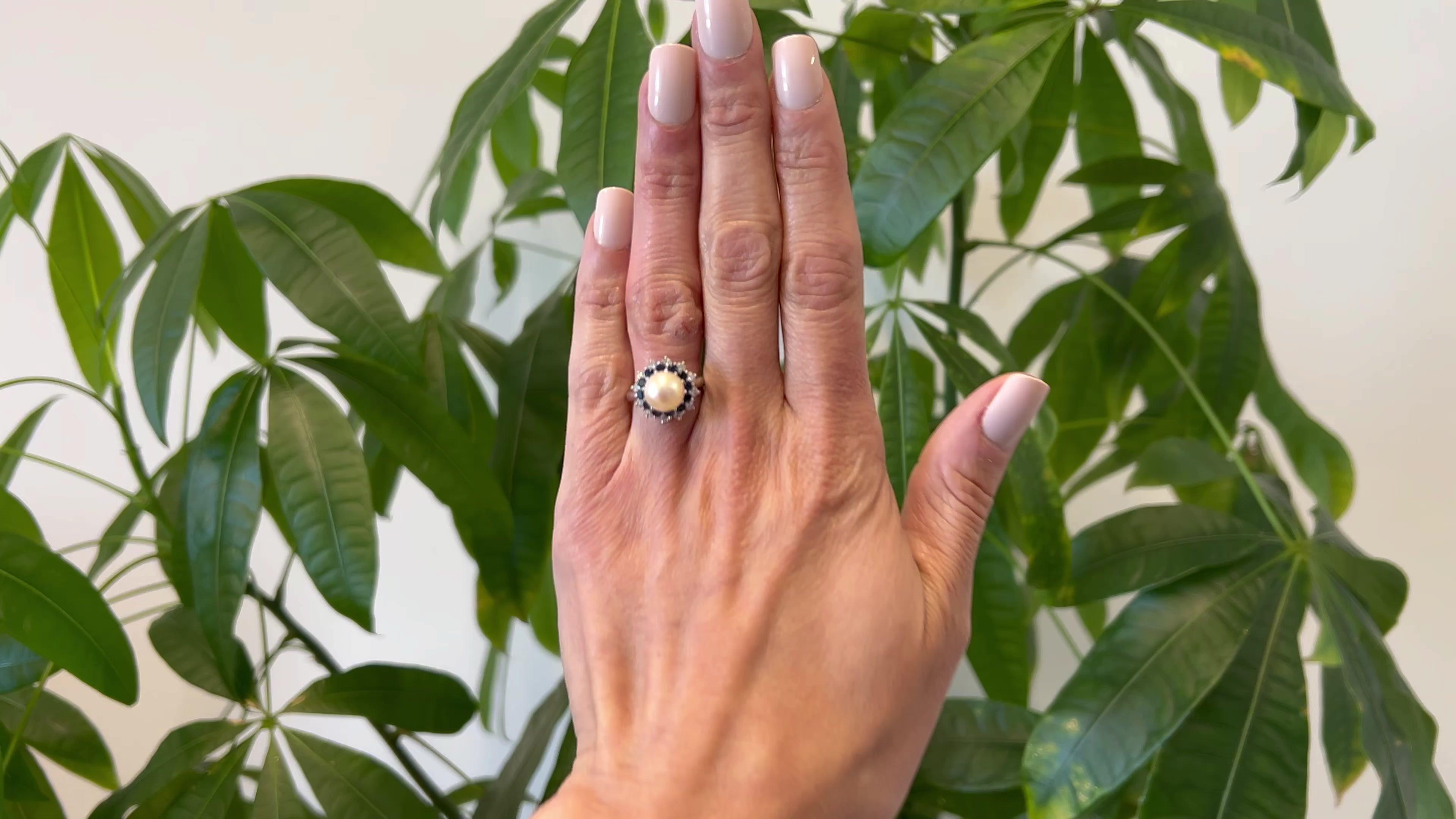 One Mid Century Tiffany & Co. Pearl, Sapphire, and Diamond Platinum Ring. Featuring one cream pearl with rose overtone measuring approximately 8.70 millimeters. Accented by 12 round brilliant cut blue sapphires with a total weight of approximately