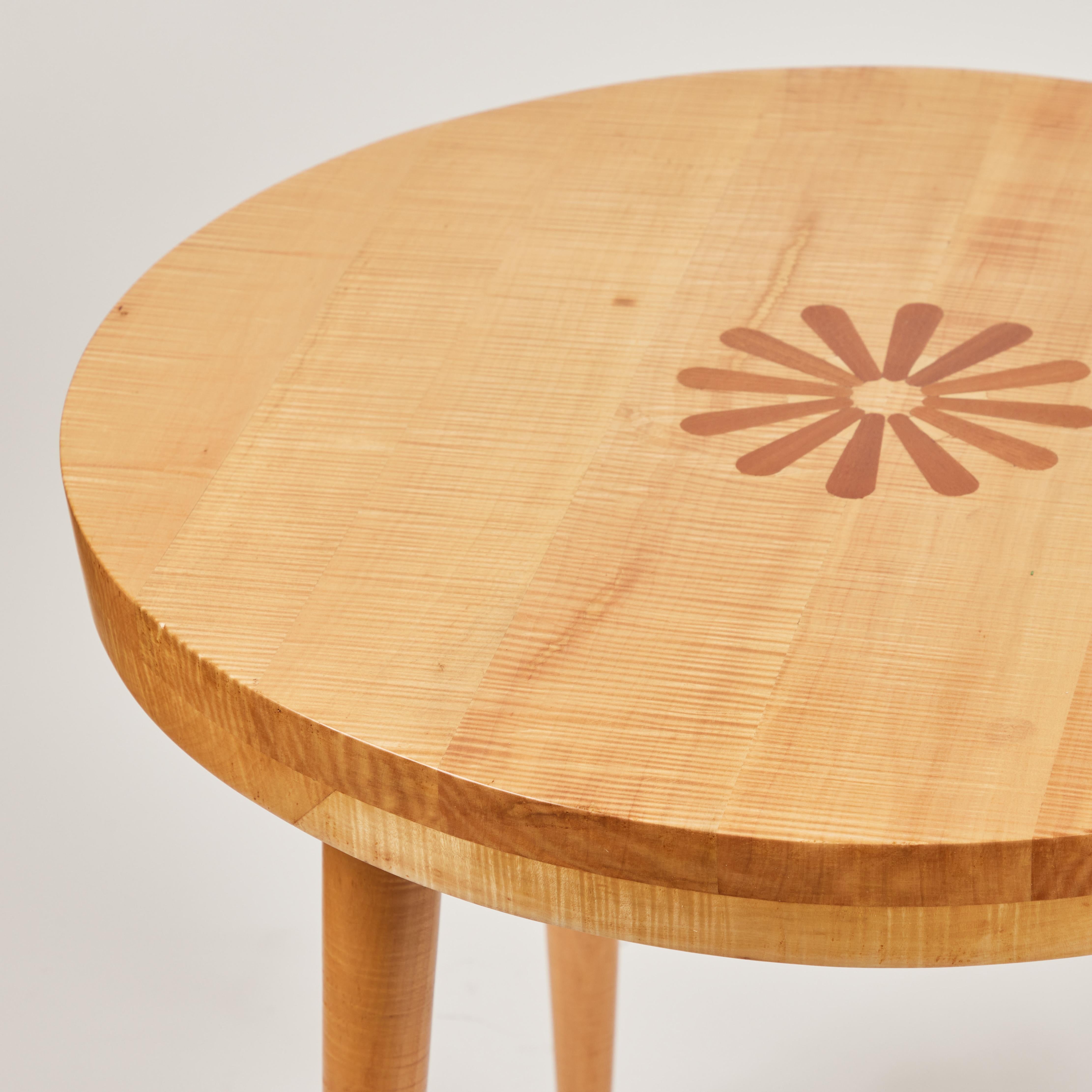 This cool mod midcentury tiger maple round side table is a real beauty. It has a decorative inlaid contrasting color wood flower design on the top center and has been newly refinished with a beautiful clear coat to showcase the outstanding