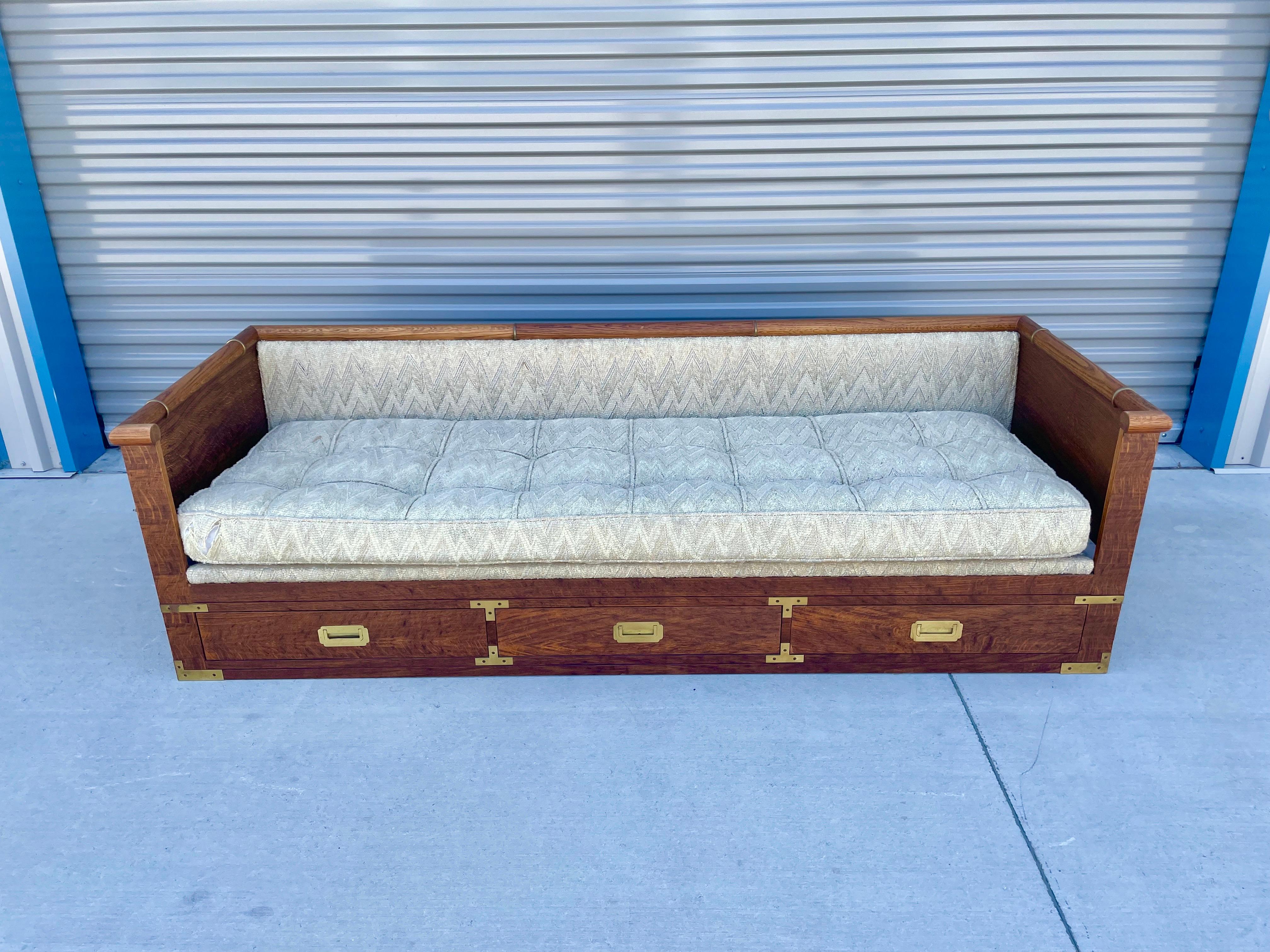 Midcentury tiger oak daybed/sofa by Marge Carson. This sofa is a wonderful piece that can use as a daybed or a sofa giving it two unique purposes. It features a tiger oak wood frame that comes with three pull-out drawers each with their solid brass