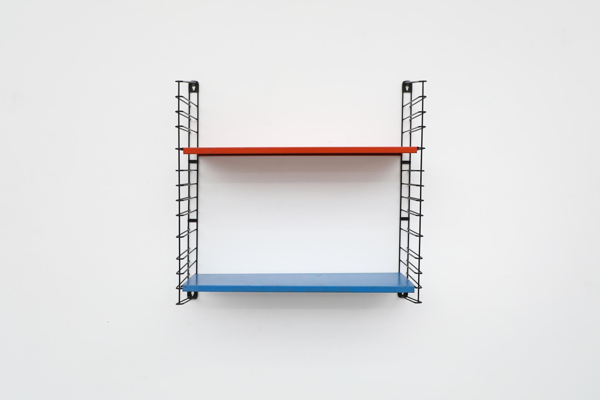 Midcentury TOMADO industrial shelving with red and bright blue shelves on black enameled metal wire risers. Designed by Jan van der Togt. The shelves rest on the wire risers and can be arranged to different heights. In original condition with