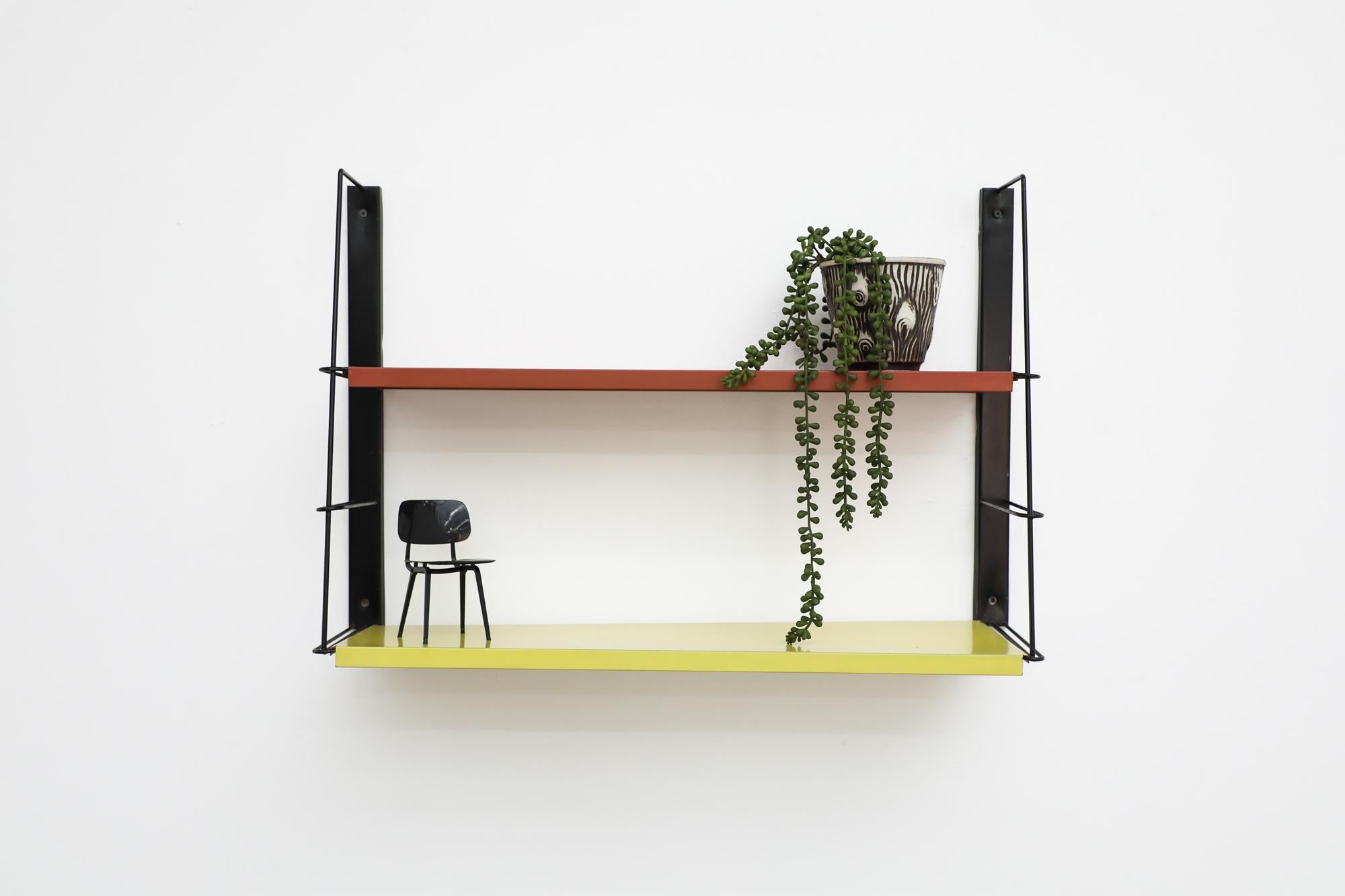 Mid-Century TOMADO Style industrial wall mount book shelf with moveable Red & Yellow sheet metal shelves on slanted black enameled wire risers. Original condition with wear and some visible enamel loss. Ships Flat. Similar units also available and