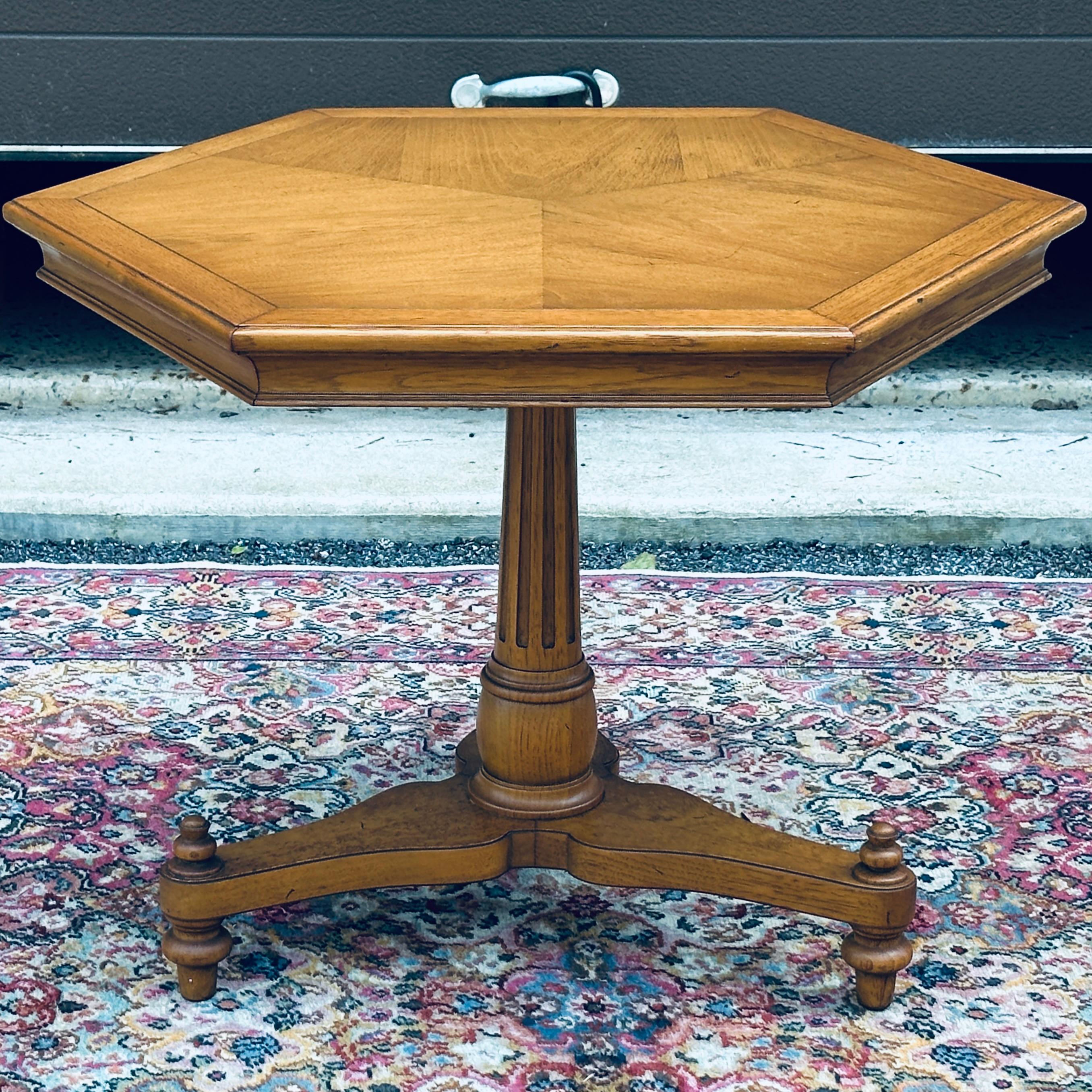 Mesa auxiliar hexagonal firmada Pavane Furniture by Tomlinson con pedestal columnar estriado sobre singular base de tres patas.