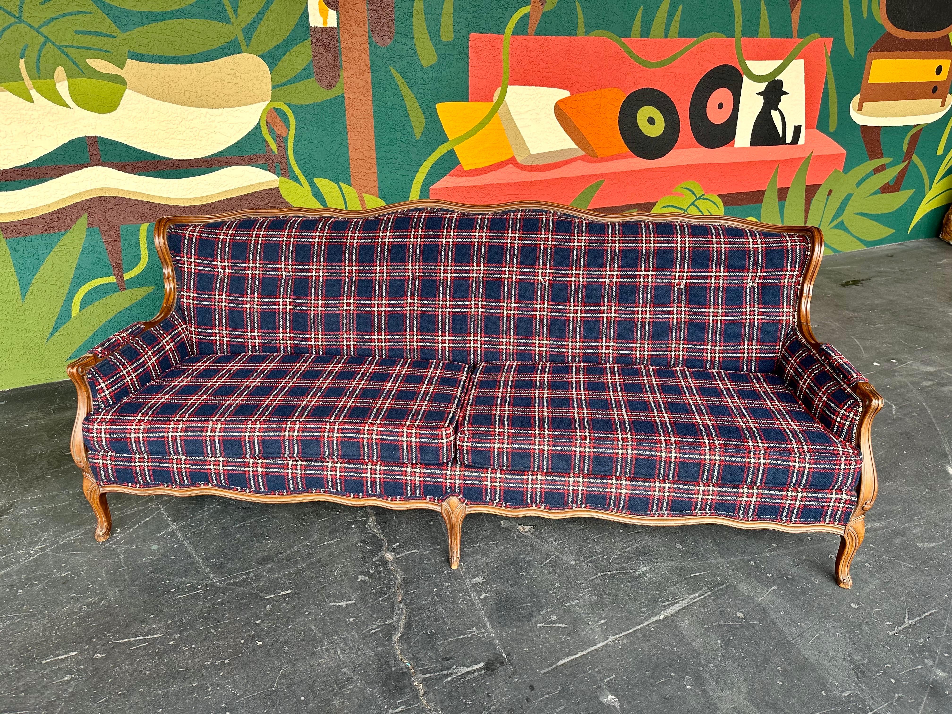 Mid Century Traditional style navy window pane wool plaid sofa with wood trim, made by Gimble Brothers c.1960’s. Lovely wingback shape with scalloped wood trim and carved feet and arms. 
Upholstery is a rich navy blue wool textured fabric with white