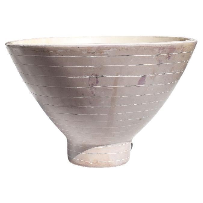 A heavy decorative stoneware bowl in pale purple. This bowl will be fabulous sitting on a coffee table, in a kitchen holding fruit, or in a foyer for holding keys and wallets. The dish is quite heavy and stands upon a small round footing. The body