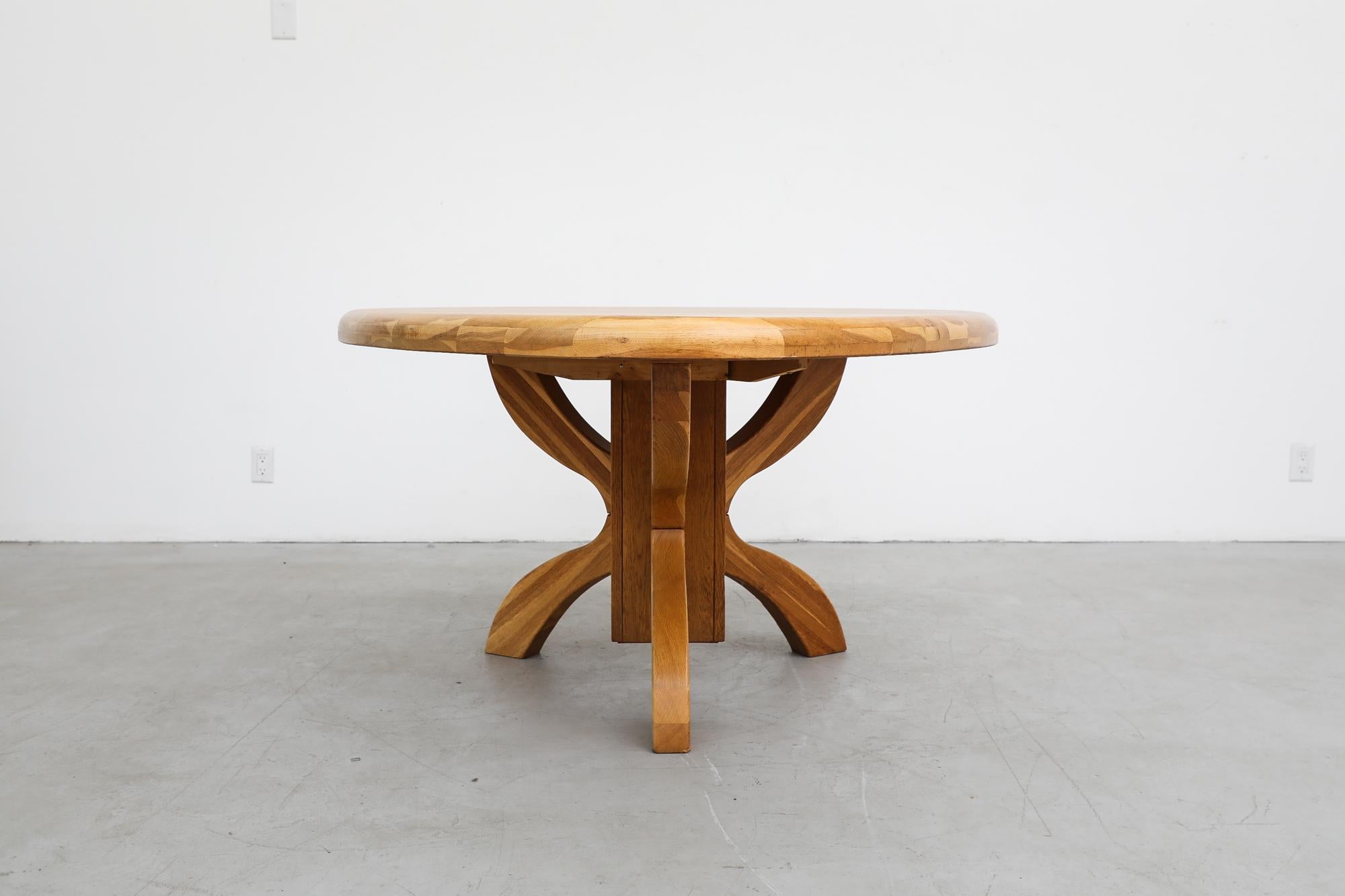 1970s solid golden oak triangular dining or center table with unique tripod pedestal base. In original condition with visible wear consistent with its age and use.
