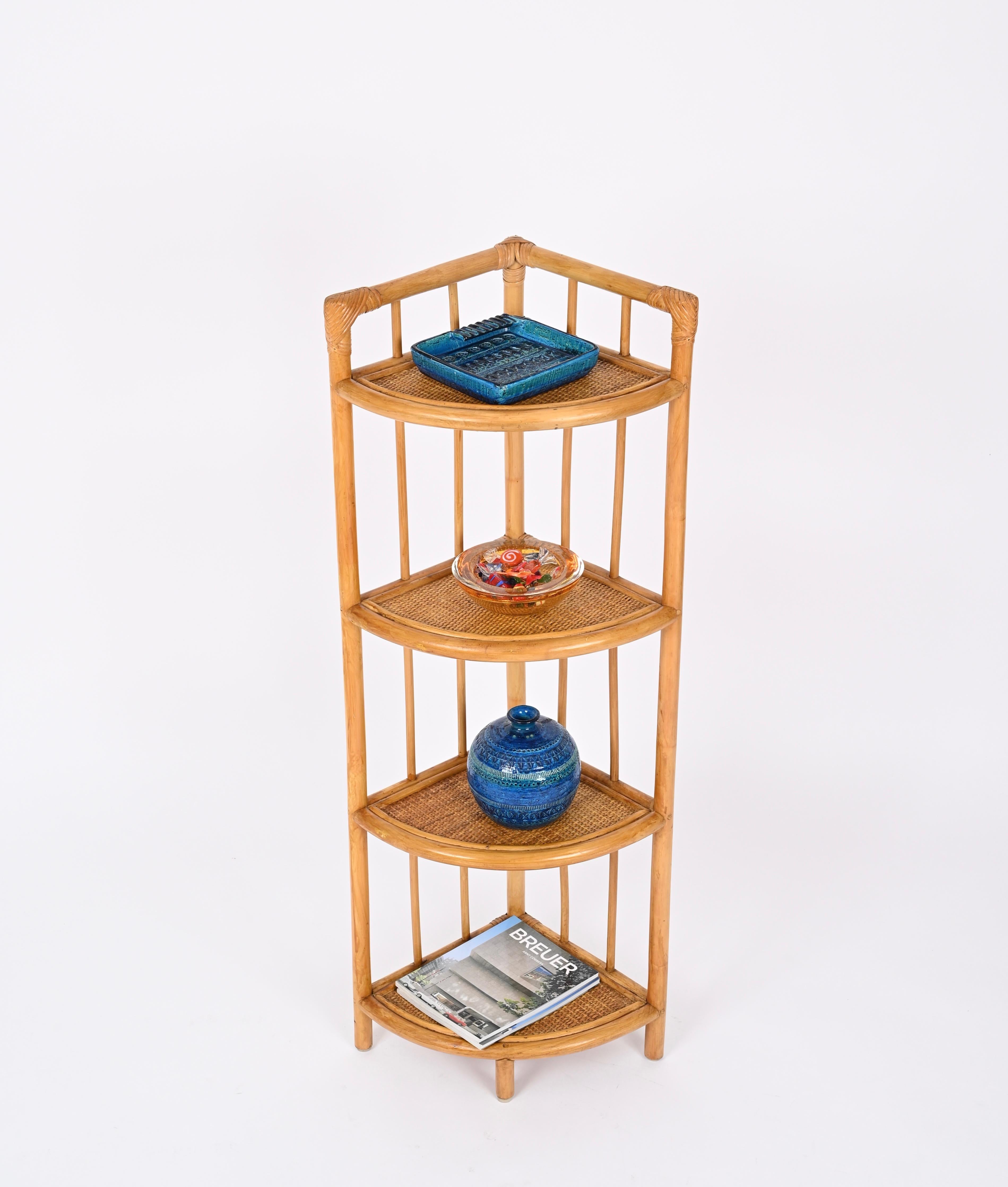 Beautiful mid-century triangular corner bookshelf made in bamboo, rattan and wicker. This lovely French Riviera style bookshelf was produced in Italy during the 1970s. 

This charming bookshelf features four triangular shelves made in curved bamboo