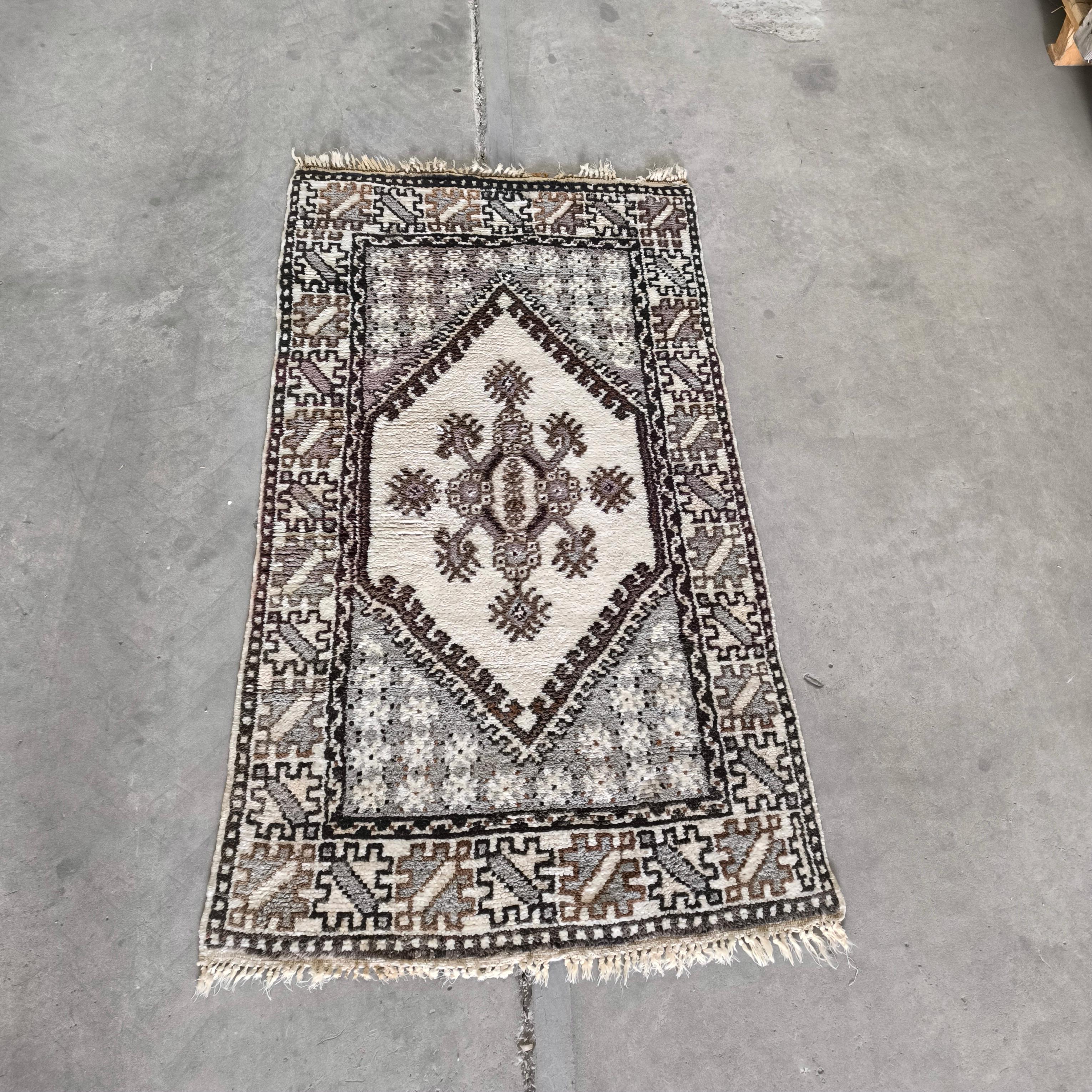 Exquisita alfombra tribal marroquí de mediados de siglo, un raro hallazgo que combina la artesanía atemporal con una discreta elegancia. 
Totalmente anudada a mano con terciopelo de lana sobre una base de lana, esta pieza muestra un refinado diseño