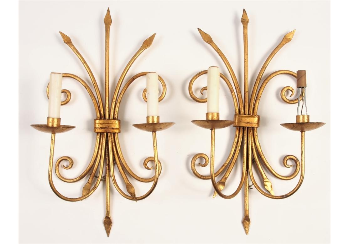 Dekoratives Paar italienischer Wandleuchten aus vergoldetem Eisen in Form eines Dreizacks mit geschwungenen Elementen. Kompaktes Design mit einer breiten und spannenden Präsentation. Elektrifiziert. 

Abmessungen: H. 21