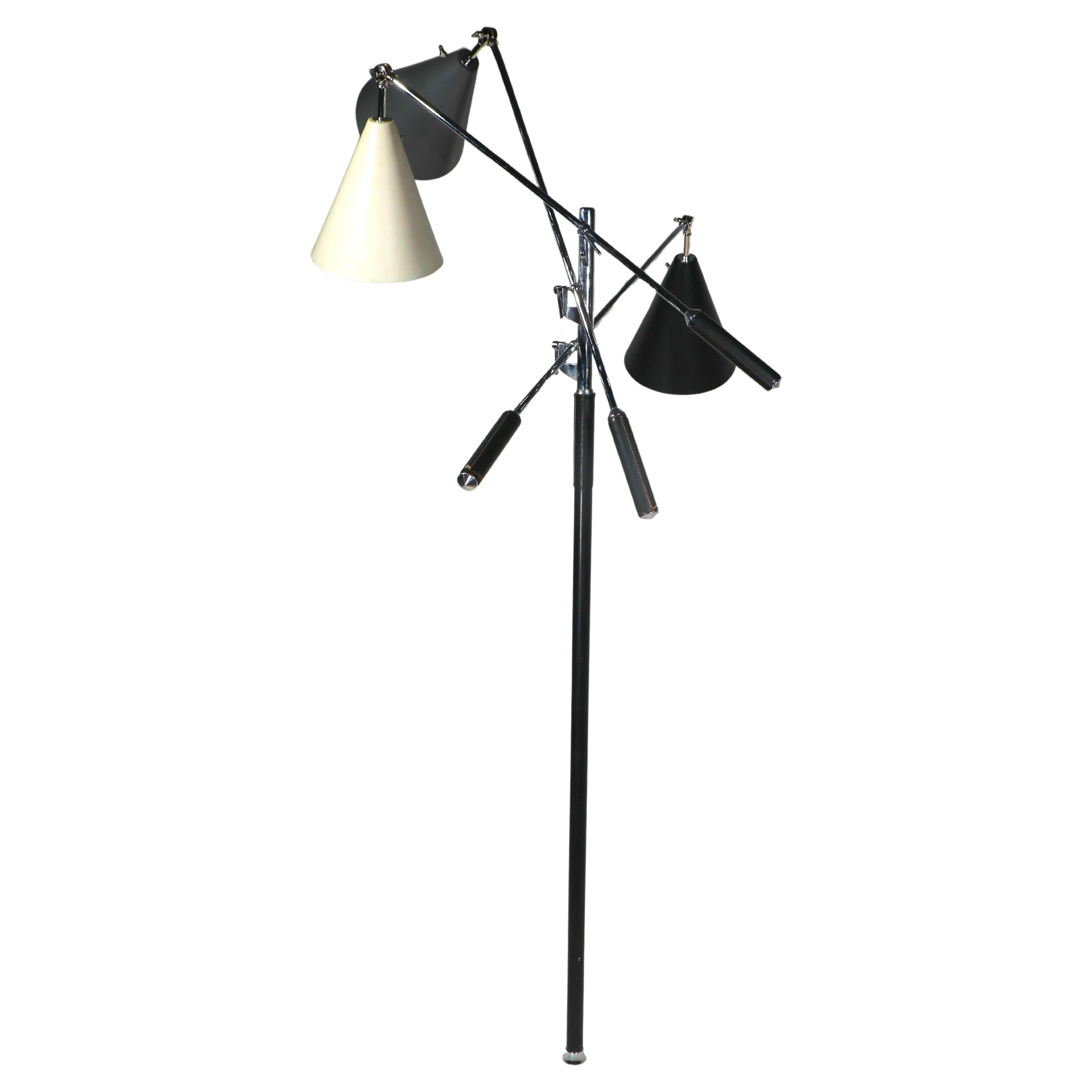 Iconic three light floor lamp, known as the Triennale, designed by Angelo Lelii, for Arredoluce, this example is marked  Made in Italy on the base and chrome figments. 
The lamp features three counter balanced arms with cone shades, one black, one