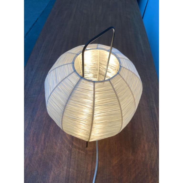 Lámpara de sobremesa Mid Century con tripartito.

El difusor redondo de trenza de bastal se asienta sobre un trípode finamente ejecutado con varillas de metal negro. La cremallera emerge de la luminaria y forma un asa en forma de arco.
Enchufe