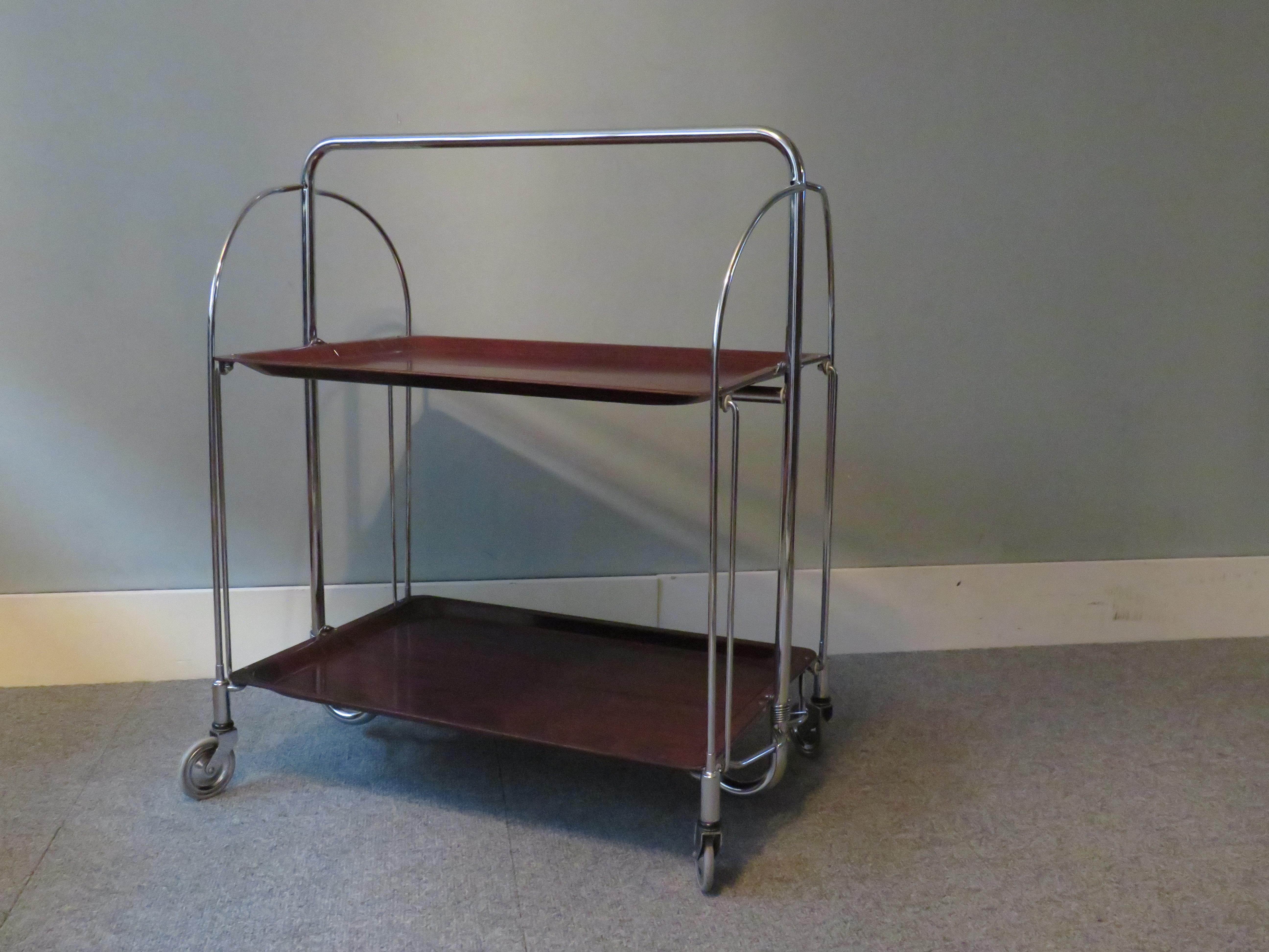 Bremshey Gerlinol Dinett trolley, after a design from 1950 by Bremshey & Co, Solingen Germany.
The trolley has a chromed steel frame and 2 folding Gerlinol blades made of pressed wood with resin coating.
It has 4 swivel wheels with rubber top