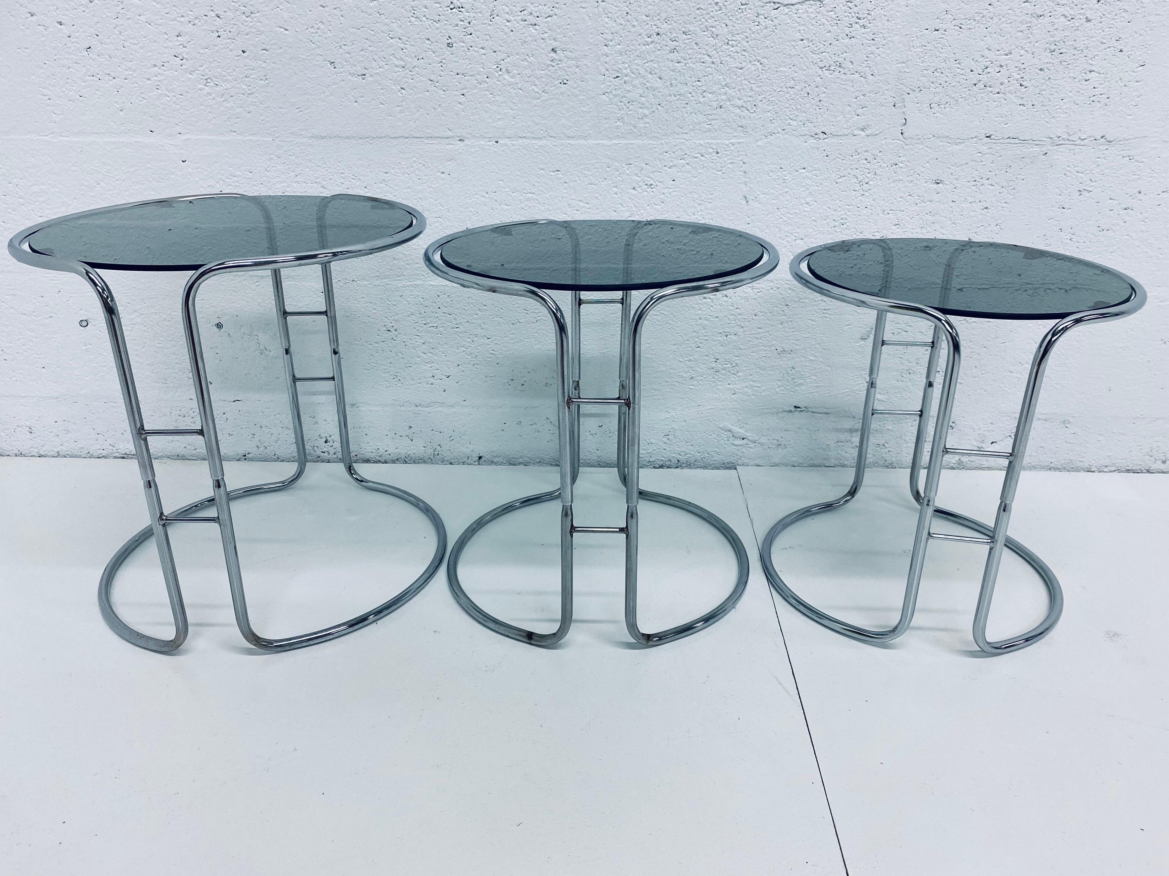 Set of three tubular chrome and smoked glass nesting tables from the 1970s. Tables stack one over the other.

Dimensions:
Large - W 17.25”, D 17.25”, H 17.25”
Medium - W 15.5”, D 15.5”, H 16.25”
Small - W 14.25”, D 14.25”, H 15.5”.