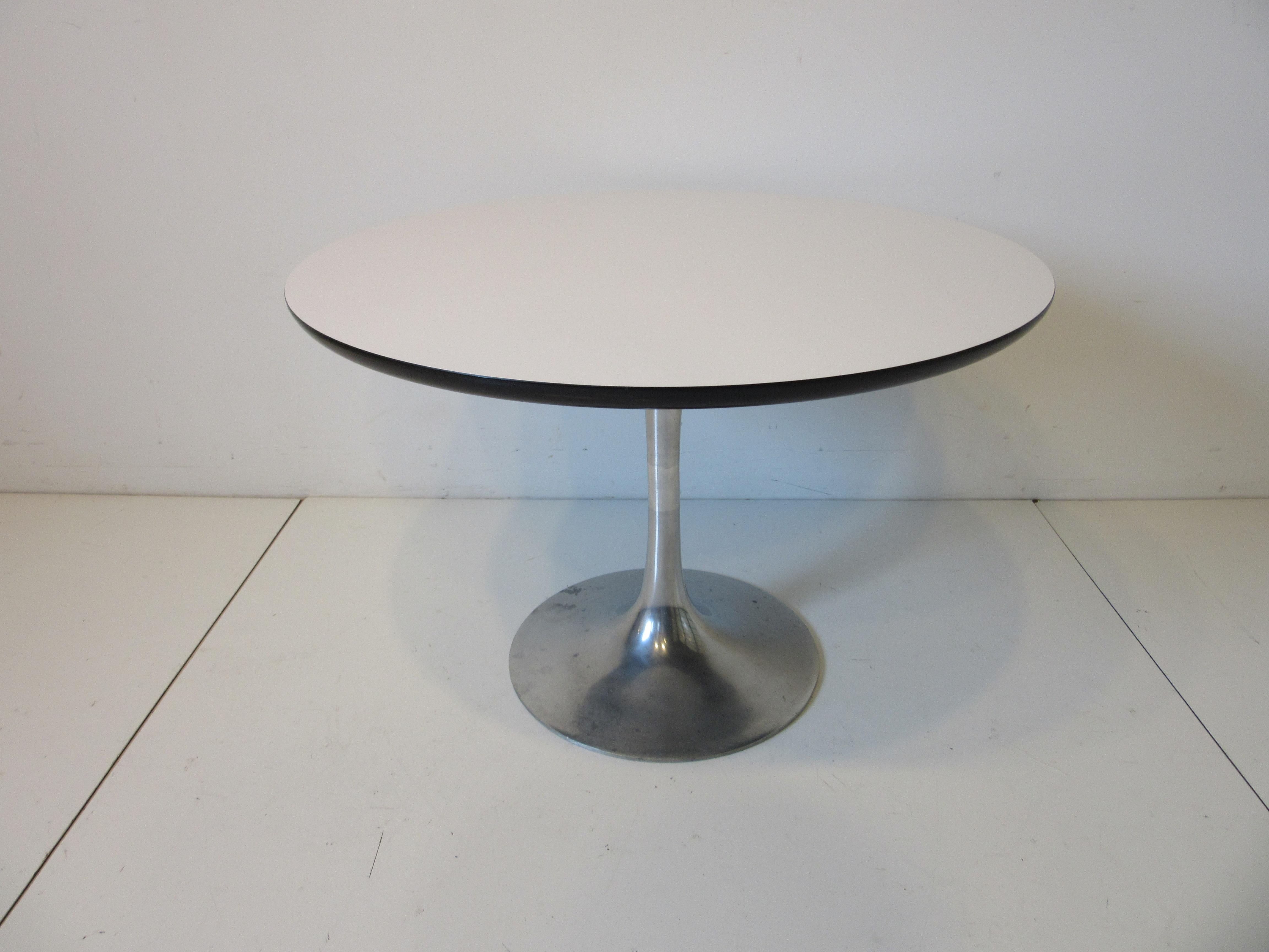 A smaller mid sized tulip side / lamp table with cast aluminum base and round white laminate top with black 
designed by Maurice Burke and manufactured by the Burke furniture company.