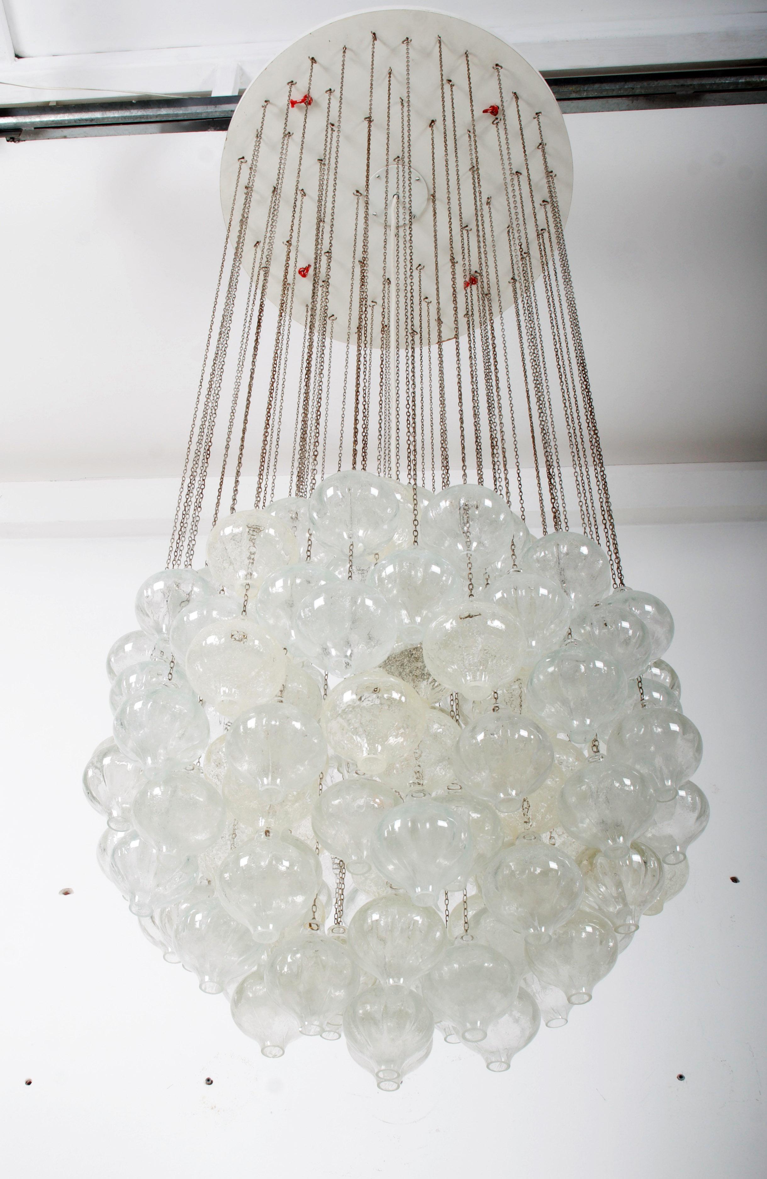 Imponente lampadario prodotto da J.AT. Kalmar a Vienna negli anni '60.
Piatto in legno dipinto di bianco con catene e 138 sfere in vetro artistico soffiato a mano. Dotato di una presa E40 fino a 500W. Condizioni originali con un po' di patina sulle