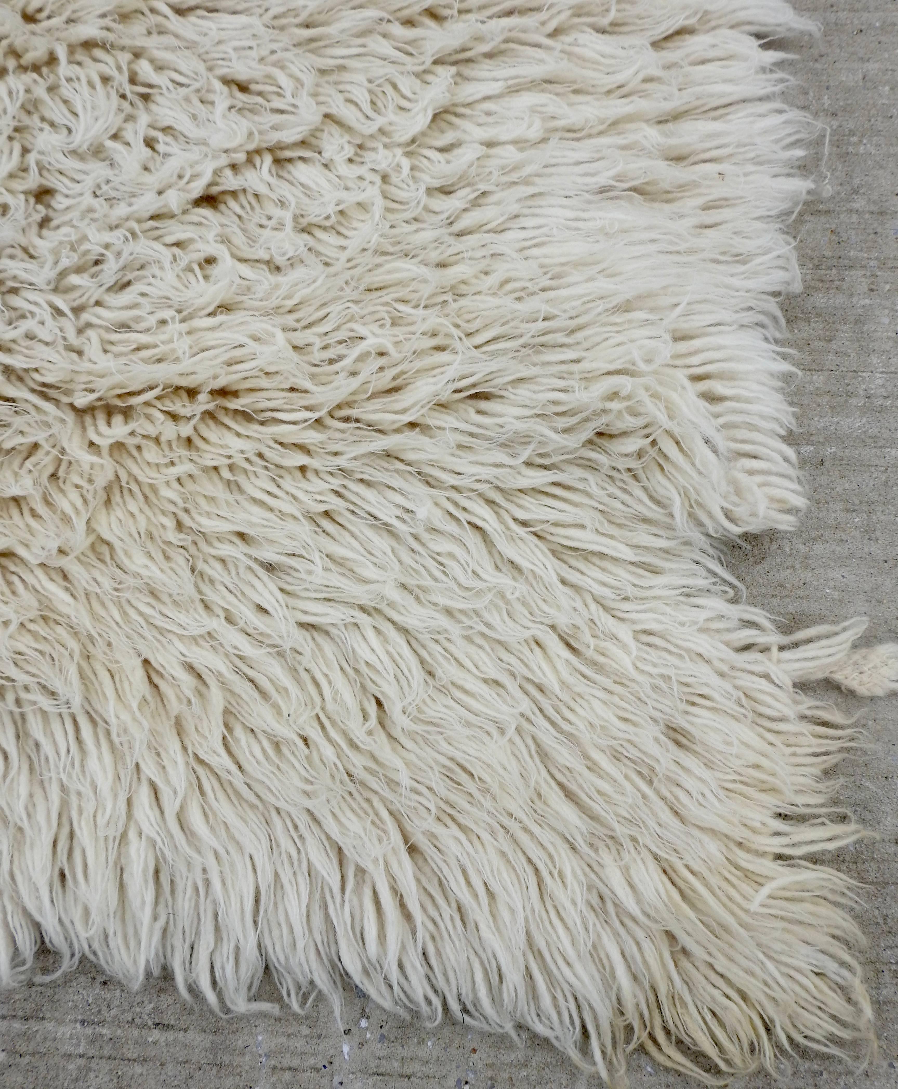 Natural fibers complete this wool Flokati rug from the midcentury era. These handmade rugs were produced for daily use by villagers around Karapinar in Central Anatolia. The rug has been hand knotted. This style of rug has a Minimalist look and is