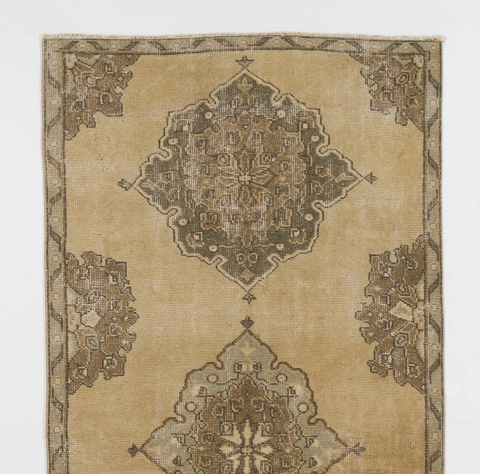 A Mid-20th century hand-knotted runner rug from Central Turkey with a nuanced color palette of neutral earthy colors including ivory, beige, taupe and light brown. The rug has low wool pile on wool foundation and has a design of multiple full and