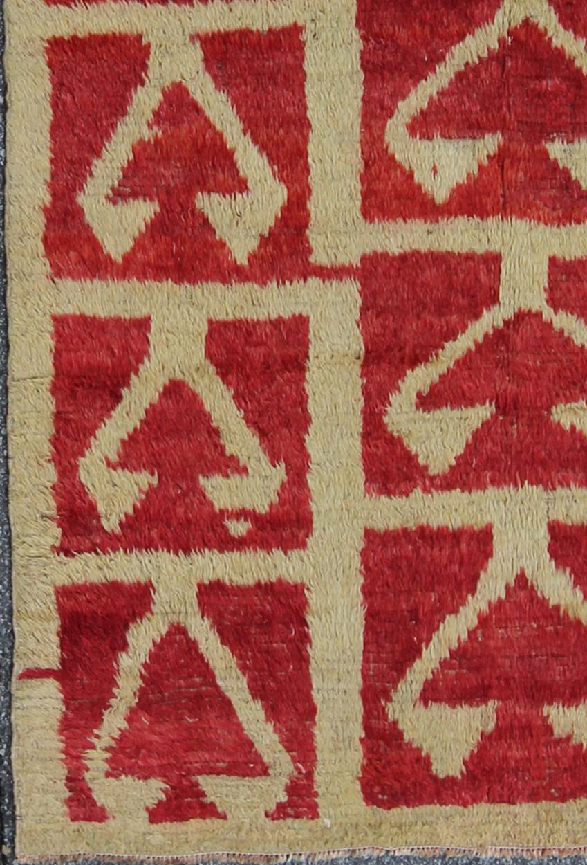 Made with very fine wool and Angora blend, this vintage Tulu from mid-20th century Turkey boasts a Mid-Century Modern design with an interconnected tribal pattern. The multi-tiered pattern consists of off-white outlines set on a red field. The