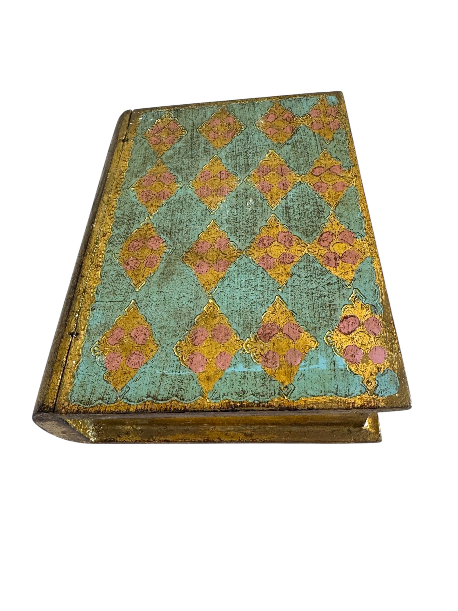 Magnifique exemple de l'artisanat florentin classique, cette boîte à livres turquoise et or capture le charme des arts décoratifs italiens. Peint à la main et doré avec une riche patine, il imite la forme d'un livre ancien tout en servant de boîte