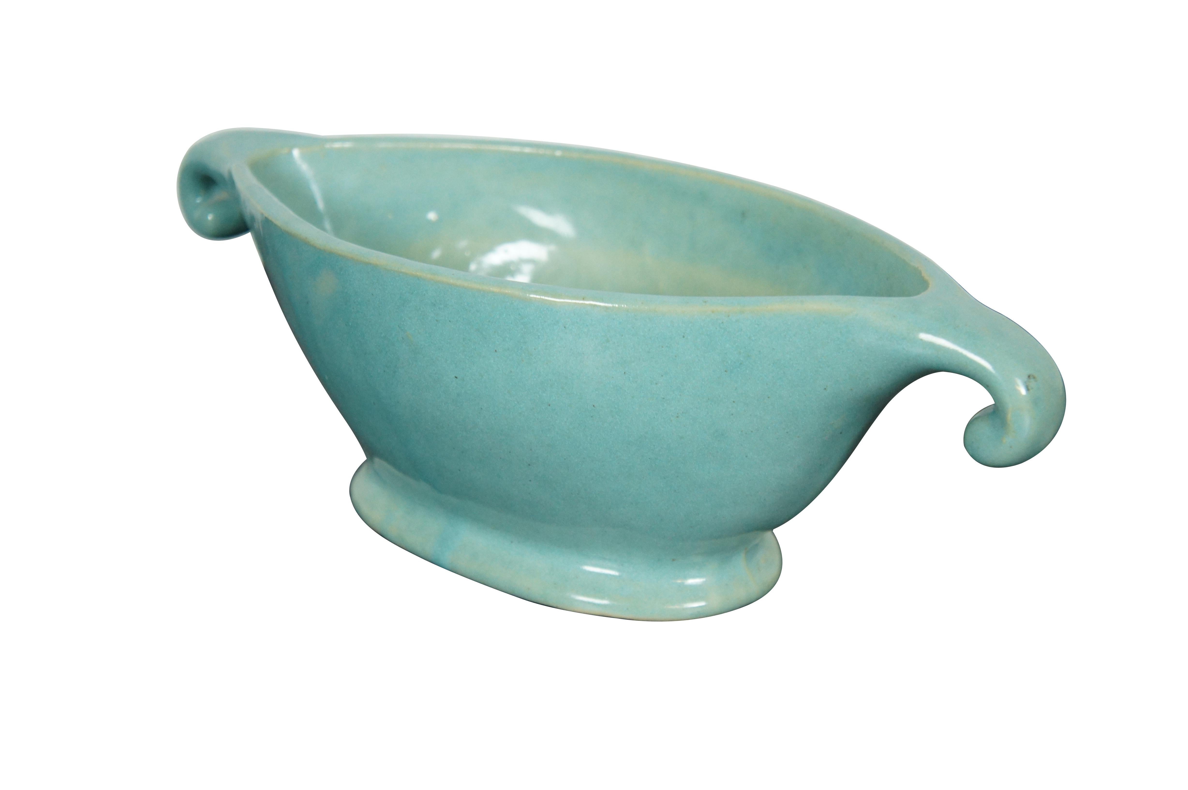 Circa mid 20th century ceramic cachepot / planter / jardiniere / urn, featuring oval Neoclassical styling with downward curling ends and footed base. Glazed in light blue / turquoise.

Dimensions:
13
