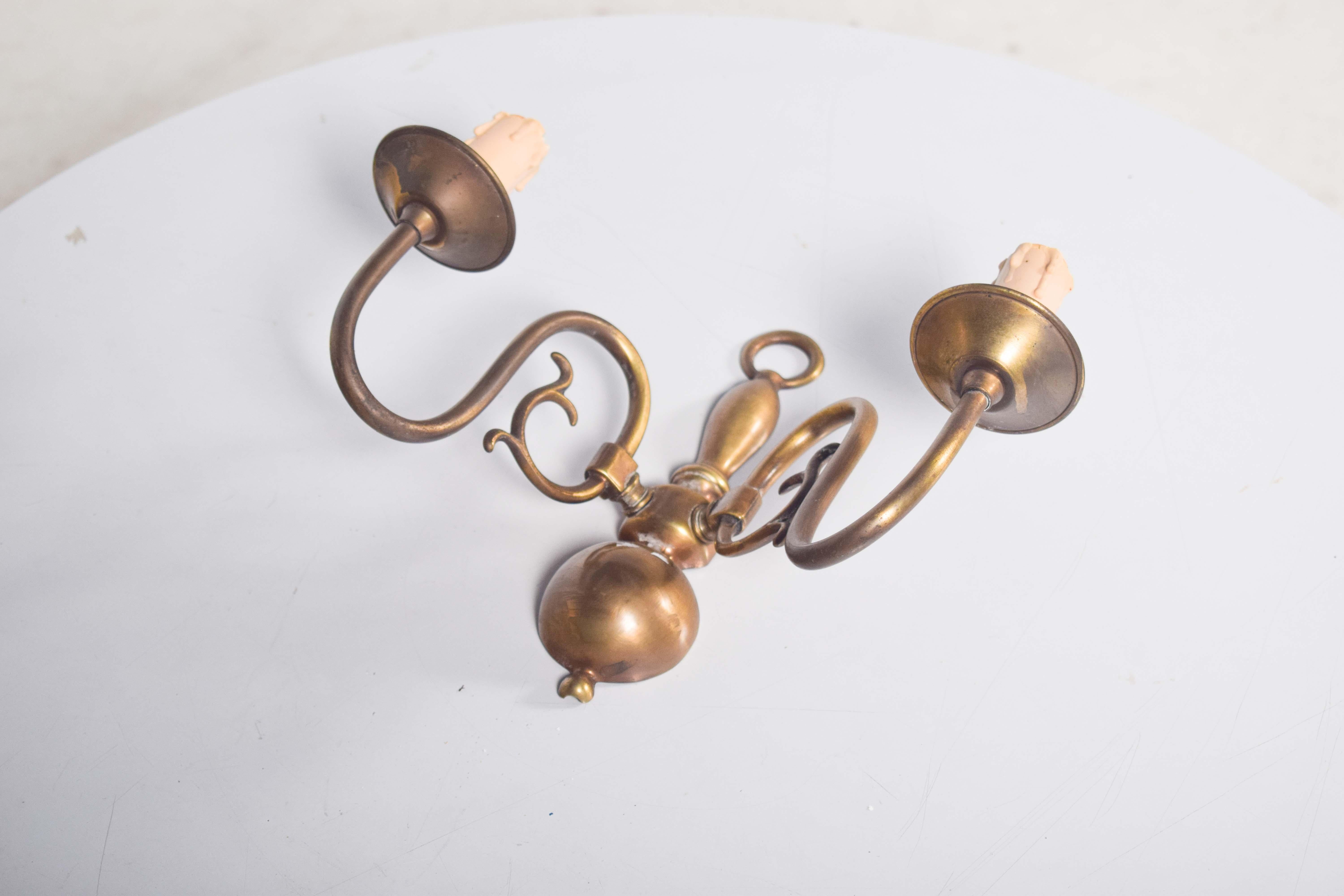 Questa elegante applique a due bracci in ottone emana un fascino vintage e senza tempo. I bracci a serpentina si curvano graziosamente verso l'esterno dal corpo centrale, creando una silhouette equilibrata e fluida. Il corpo, sottile e affusolato,